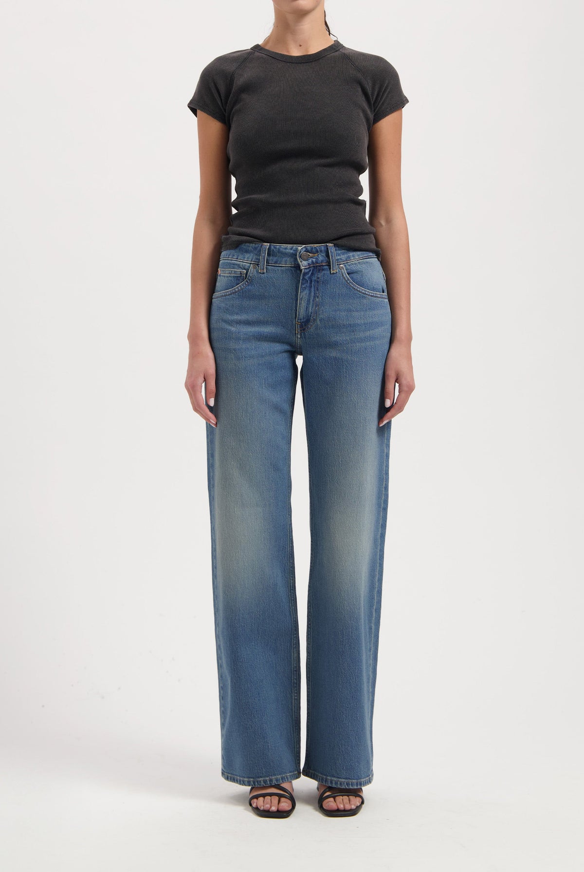 Wide-leg blue jeans with faded effect, paired with a fitted black short-sleeve top, worn by a model against a plain background.