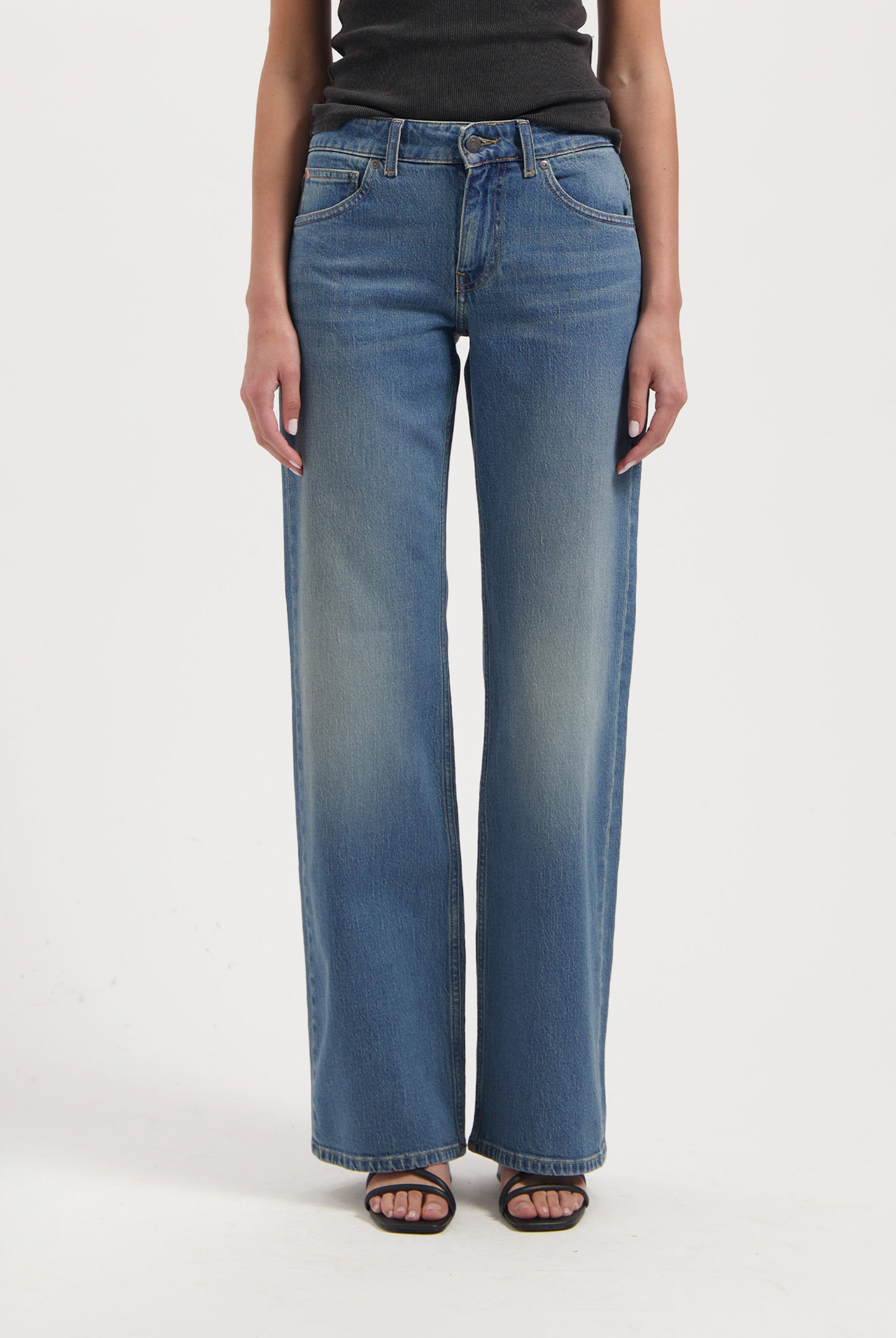 Wide-leg blue jeans with a faded wash, high waist, and classic five-pocket design, paired with a black sleeveless top.