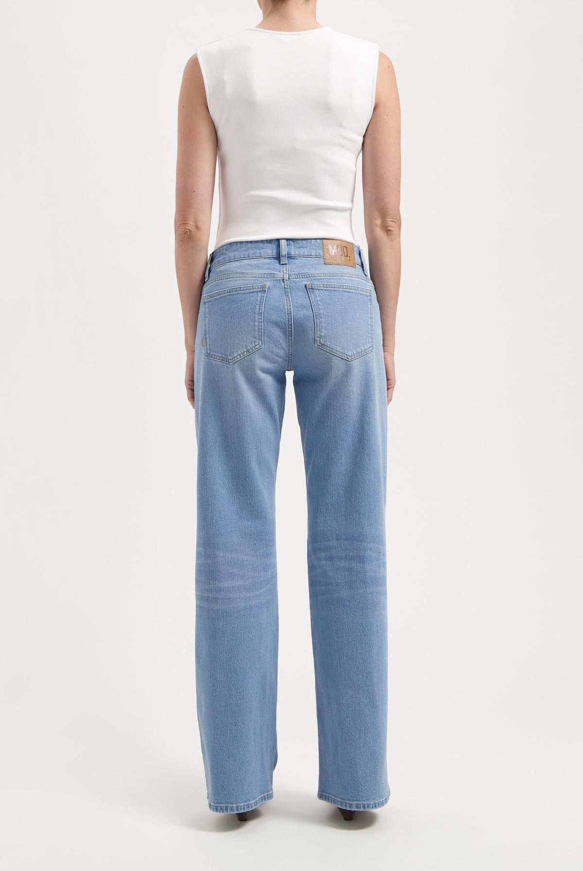 Back view of light blue, wide-leg jeans paired with a sleeveless white top, showcasing casual fit and sustainable material.