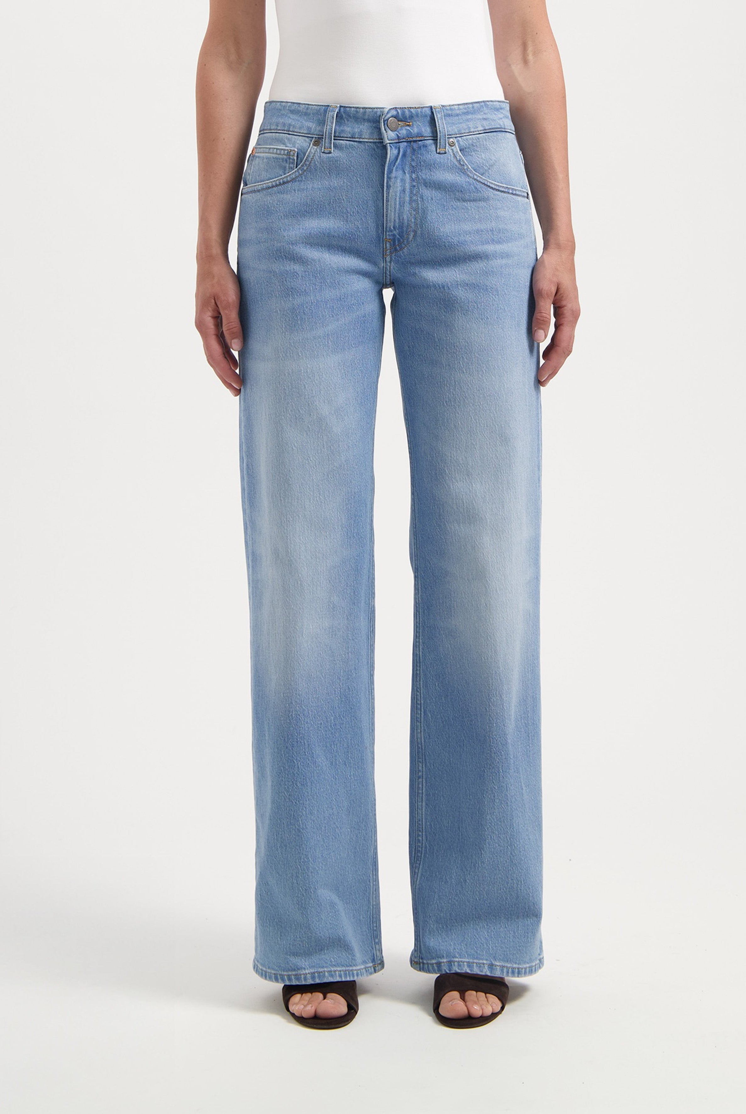 Wide-leg denim jeans in light blue, showcasing a casual fit, paired with a white tank top, creating a stylish casual look.