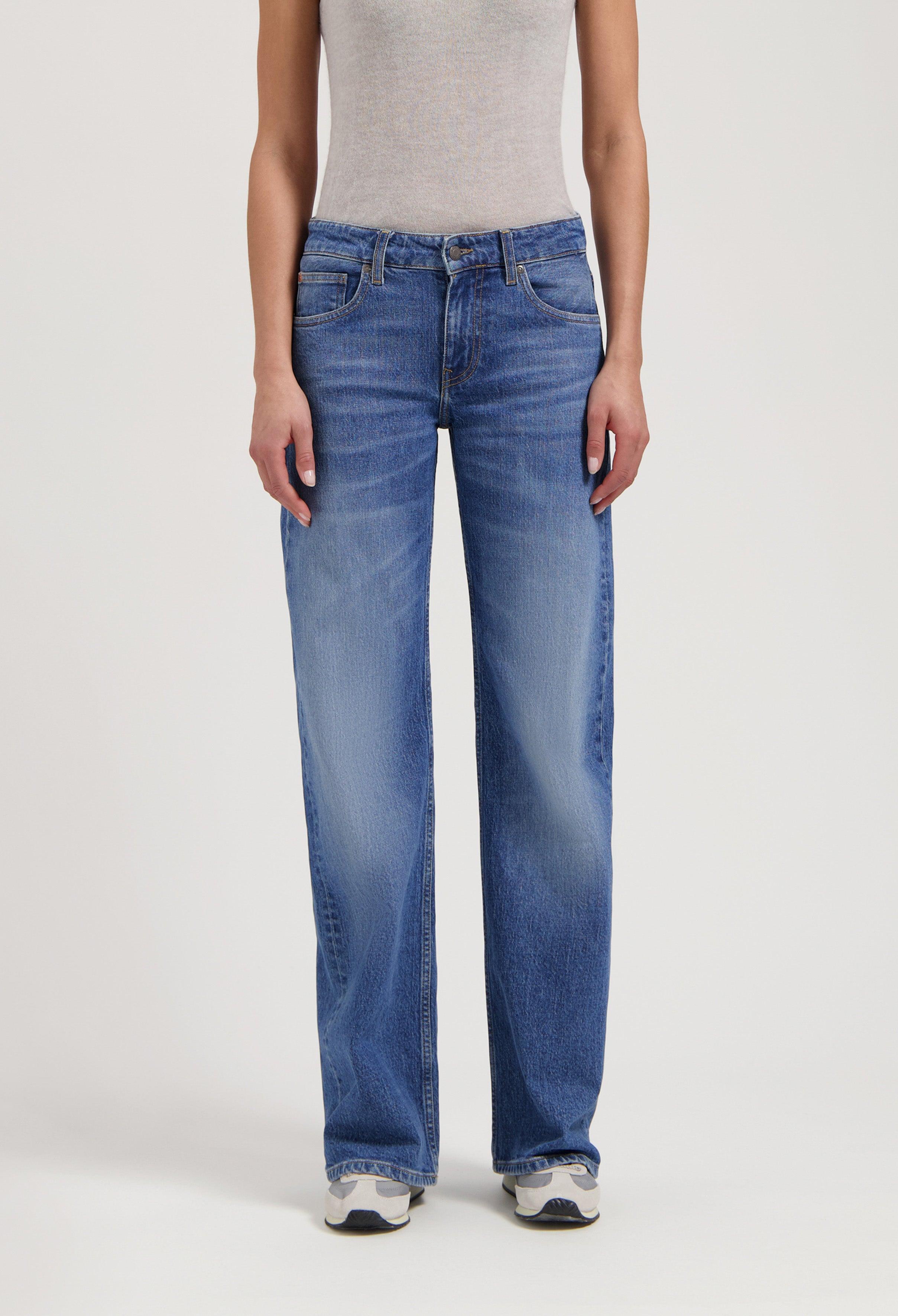 Classic blue straight-leg denim jeans worn with a gray sleeveless top, featuring a comfortable and casual style.