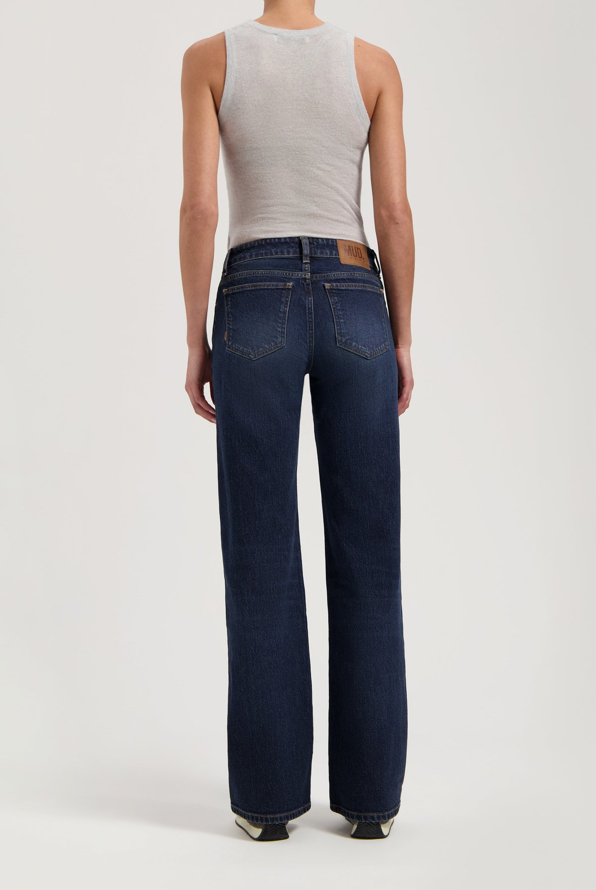 Person wearing dark blue wide-leg MUD Jeans crafted from sustainable organic cotton paired with a sleeveless gray top.