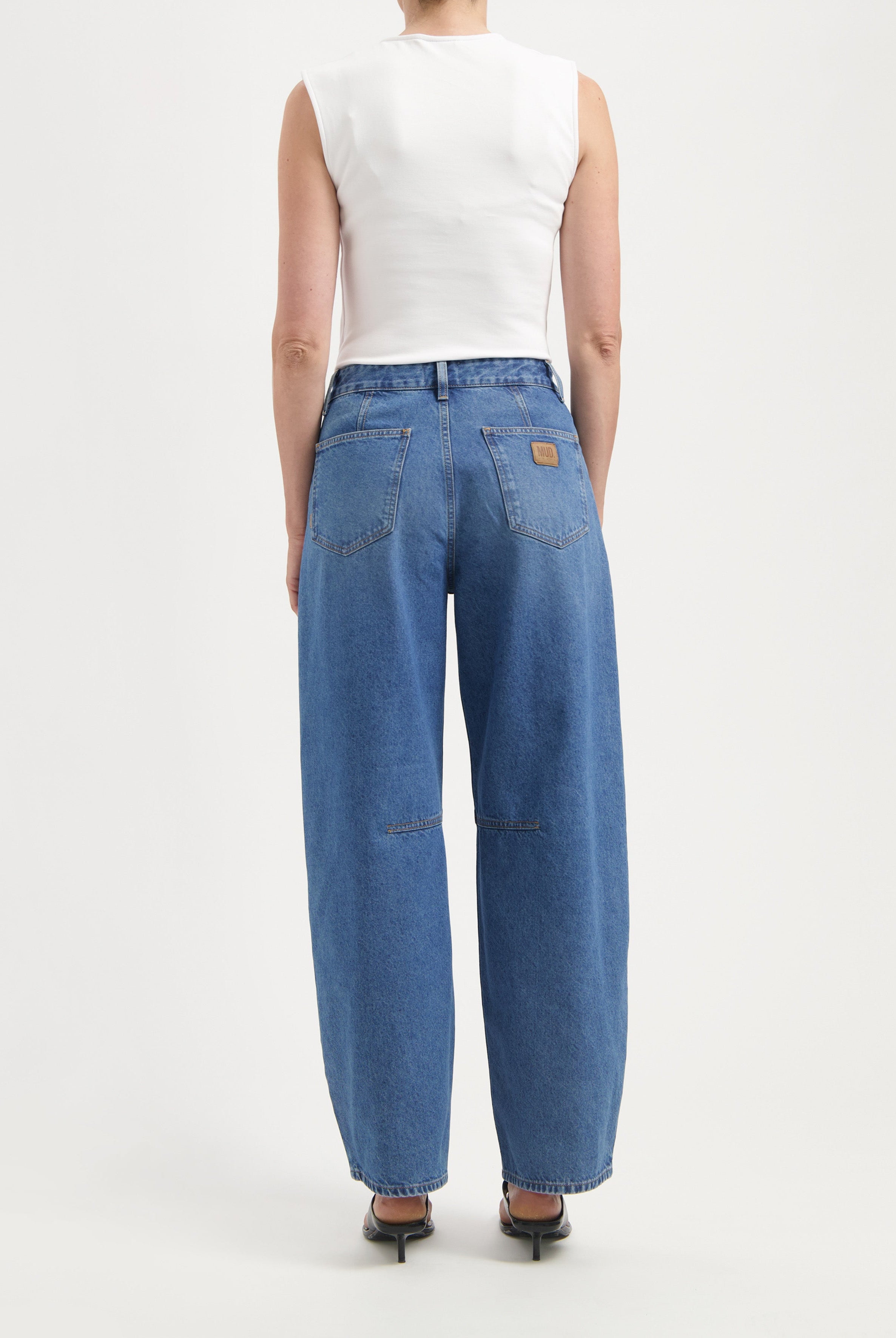 Back view of wide-leg blue denim jeans paired with a sleeveless white top, showcasing casual style and comfort.