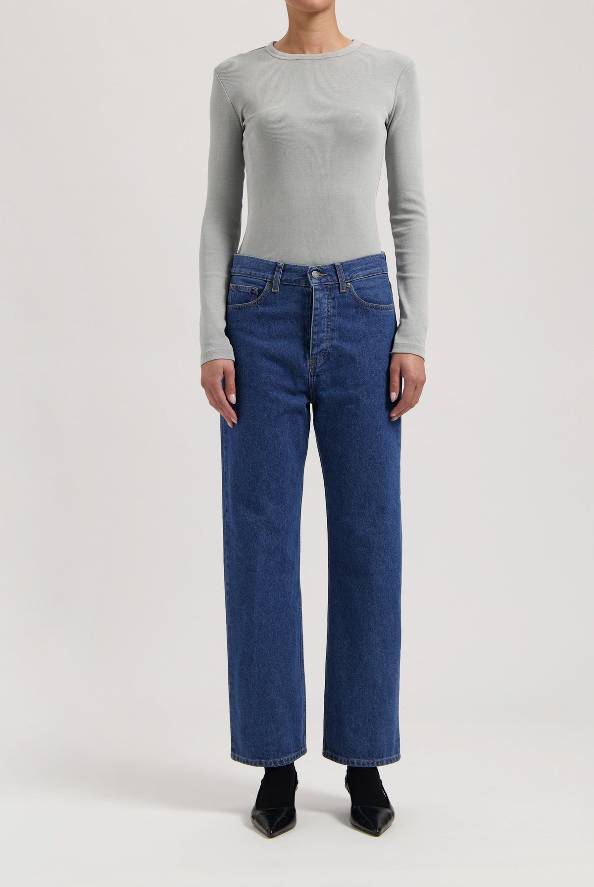 Gray long-sleeve top paired with classic high-waisted blue denim jeans, showcasing casual chic fashion style.