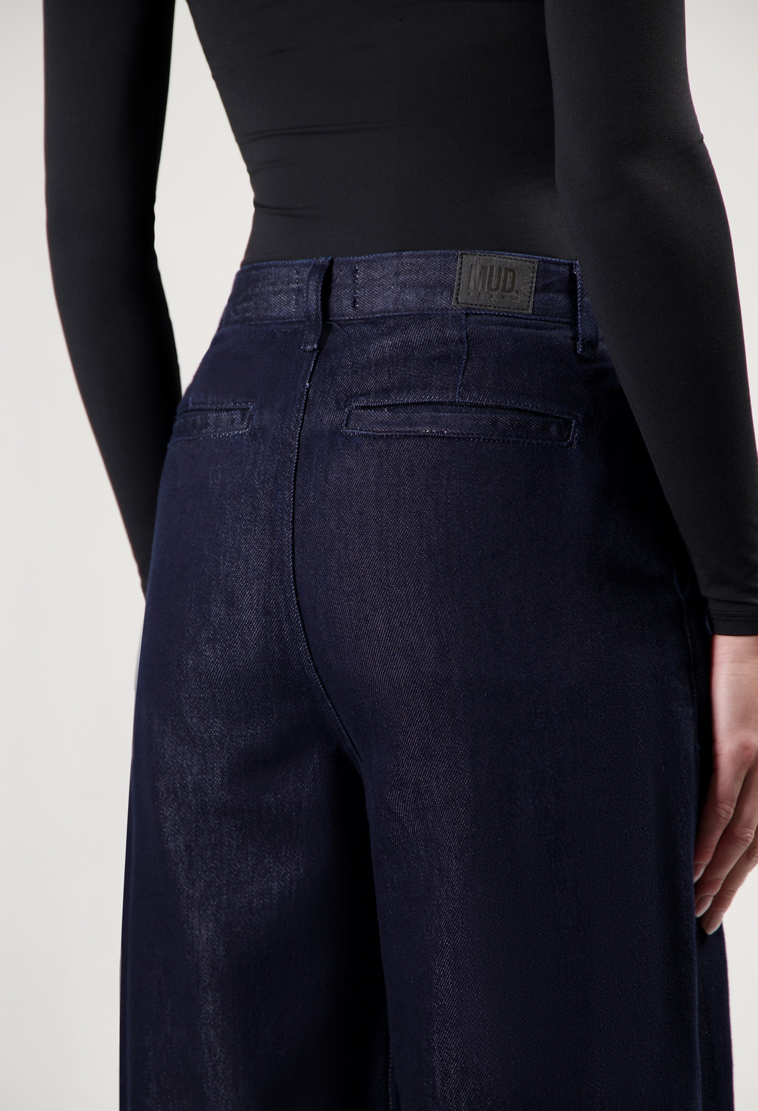 Dark indigo wide-leg denim pants from MUD Jeans, featuring a high-waisted fit, shown with a black long-sleeve top.