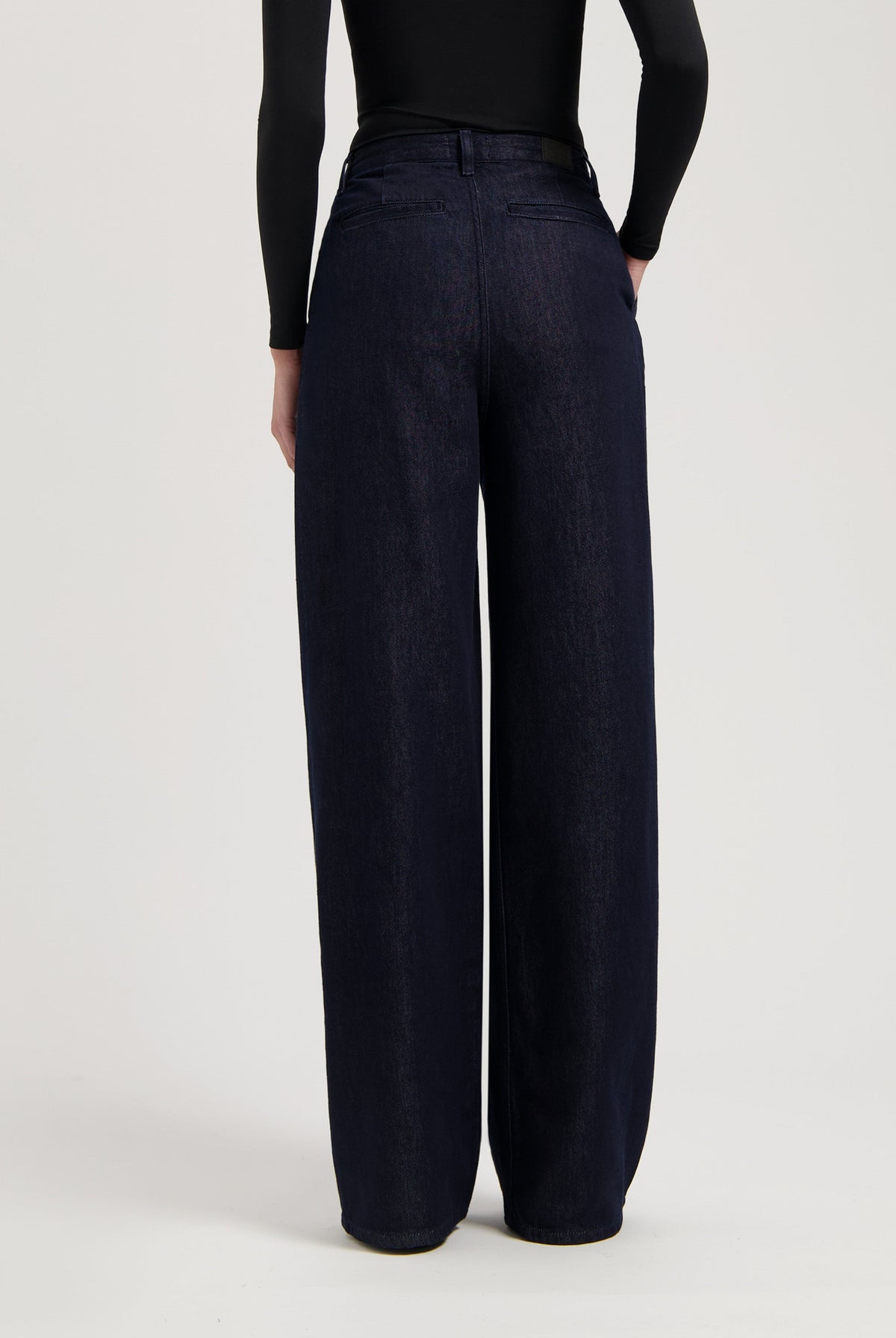Wide-leg dark indigo denim jeans with a high waist, shown from the back, paired with a long-sleeve black top.