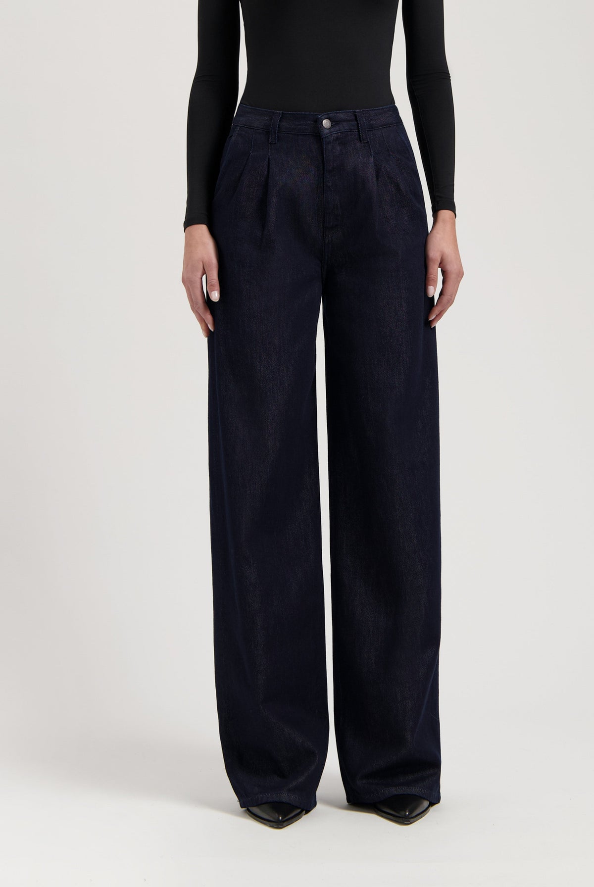 Wide-leg, high-waisted dark blue denim jeans paired with a fitted black long-sleeve top, highlighting elegant styling.