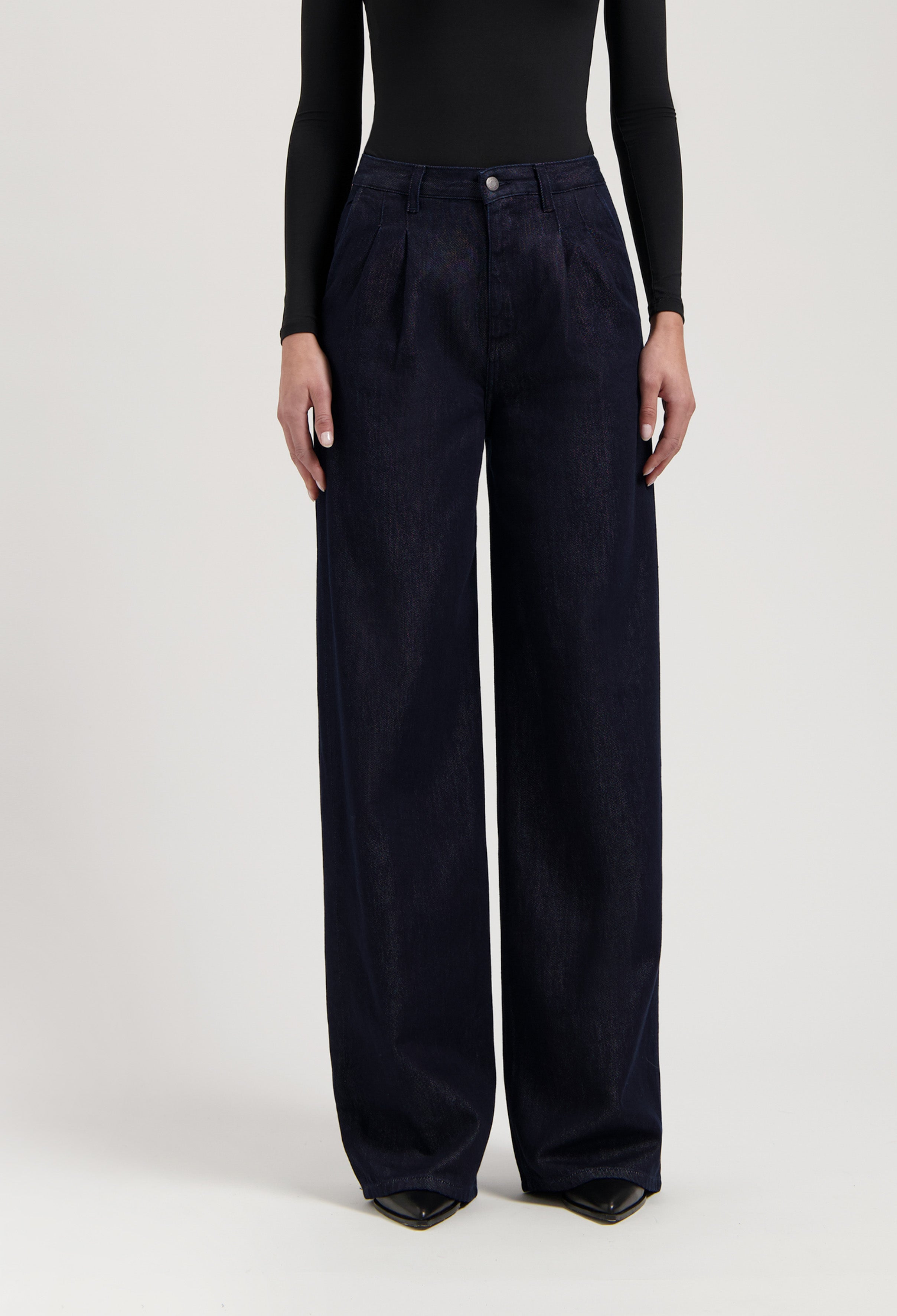 Wide-leg, high-waisted dark blue denim jeans paired with a fitted black long-sleeve top, highlighting elegant styling.