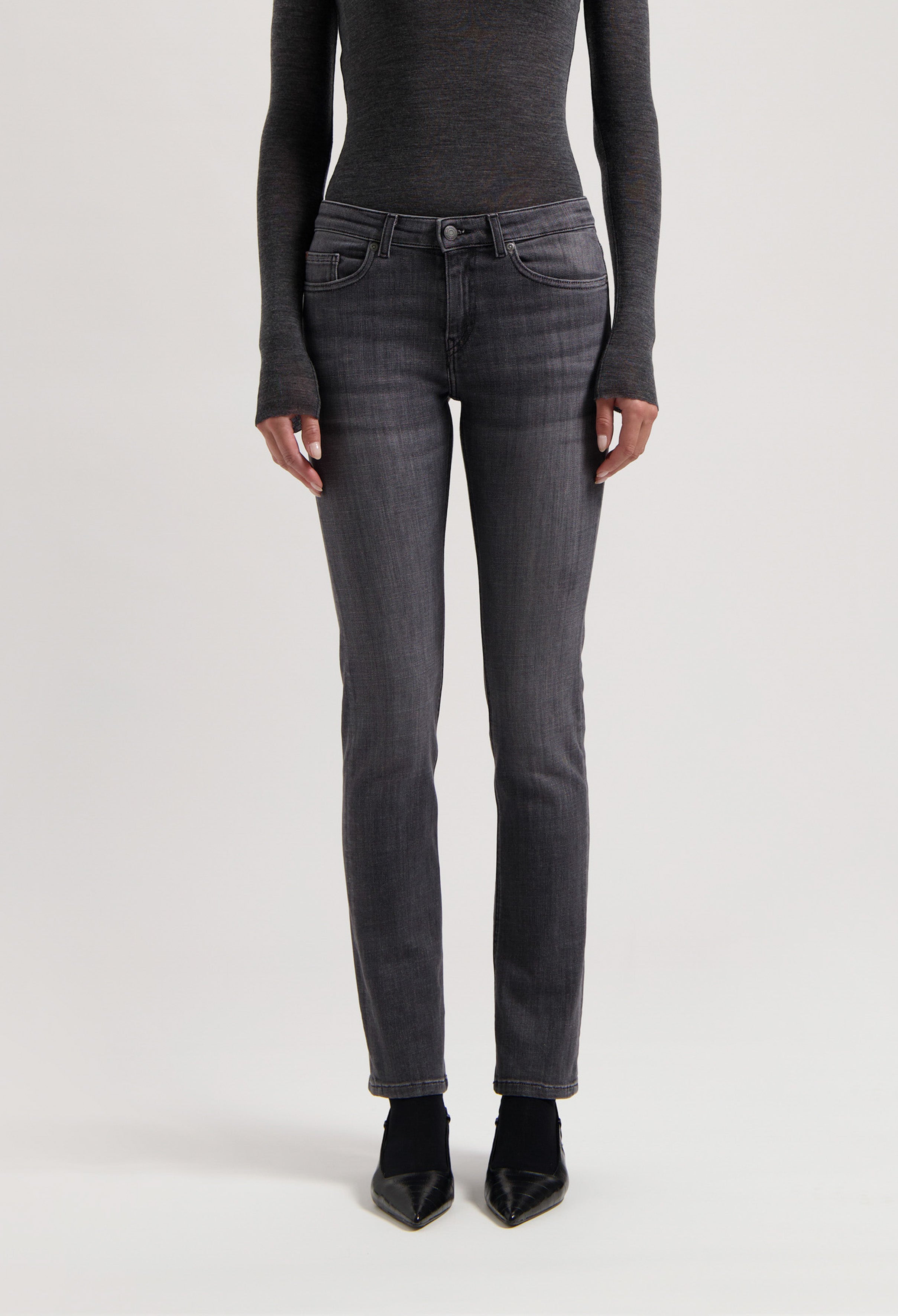 Slim-fit dark gray denim jeans styled with long-sleeve charcoal top and black pointed shoes, showcasing modern casualwear.