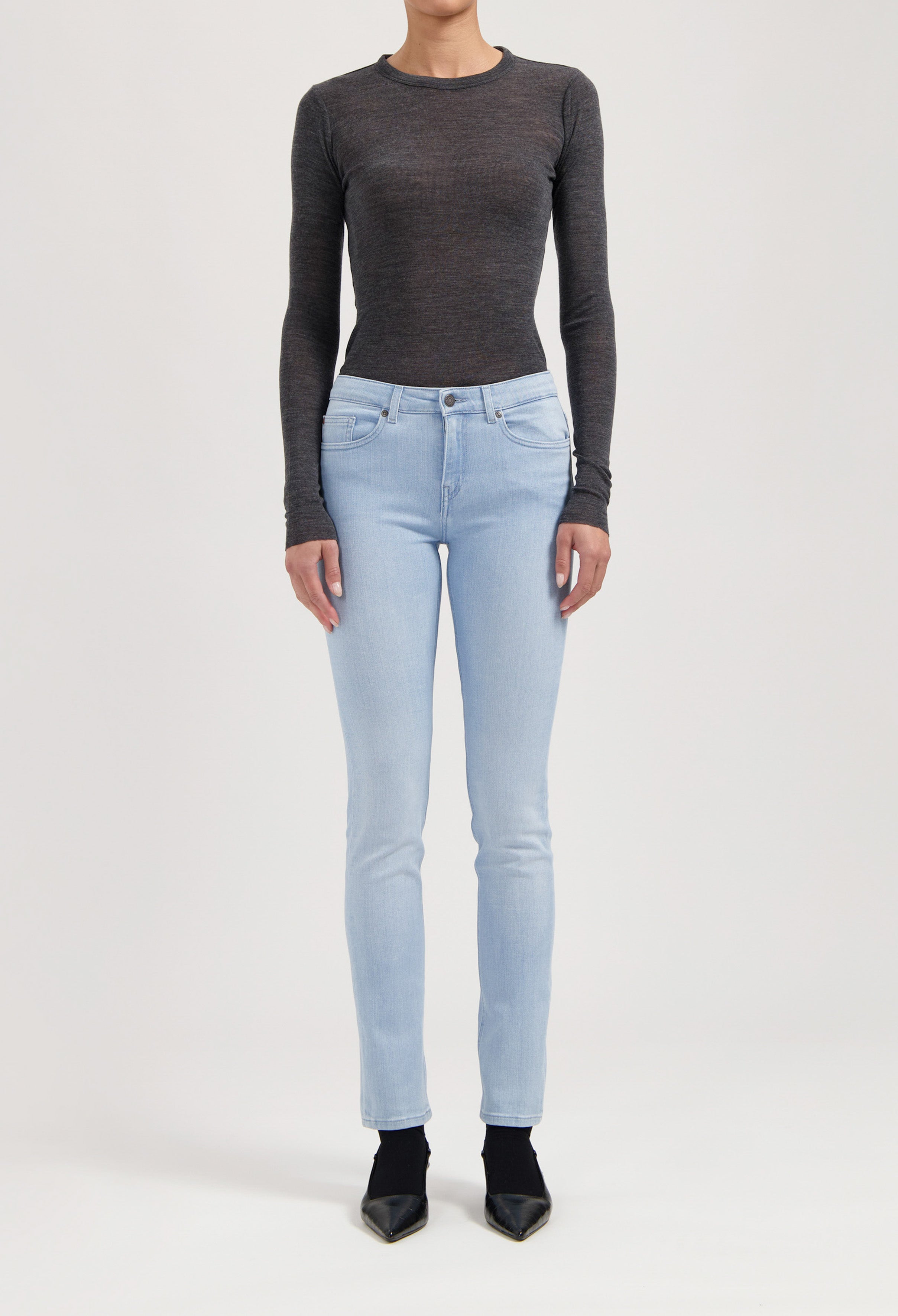 Slim-fit light blue denim jeans with a button closure, paired with a charcoal gray long-sleeve top, modeled standing.
