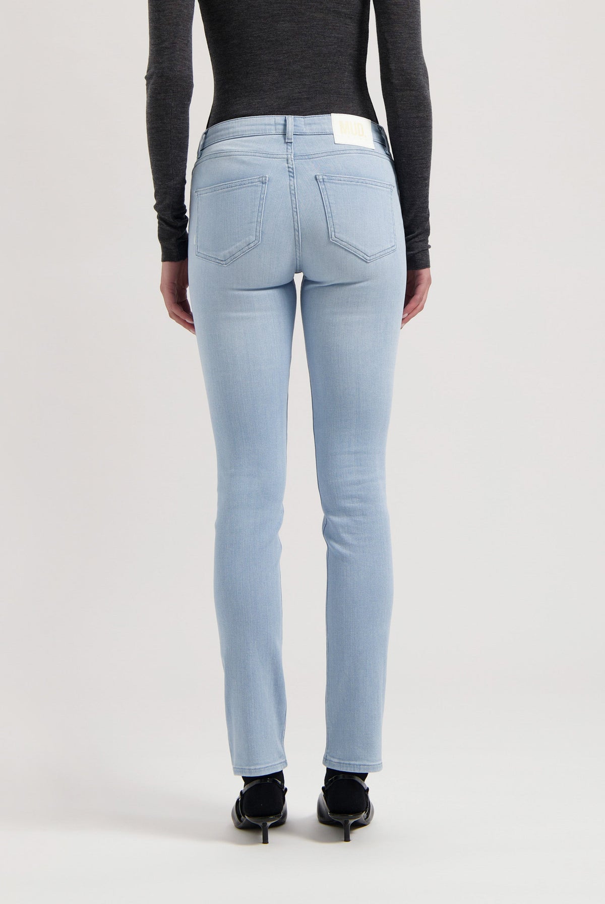 Light blue slim-fit jeans from MUD Jeans, crafted from organic cotton, shown with a charcoal gray long-sleeve top.