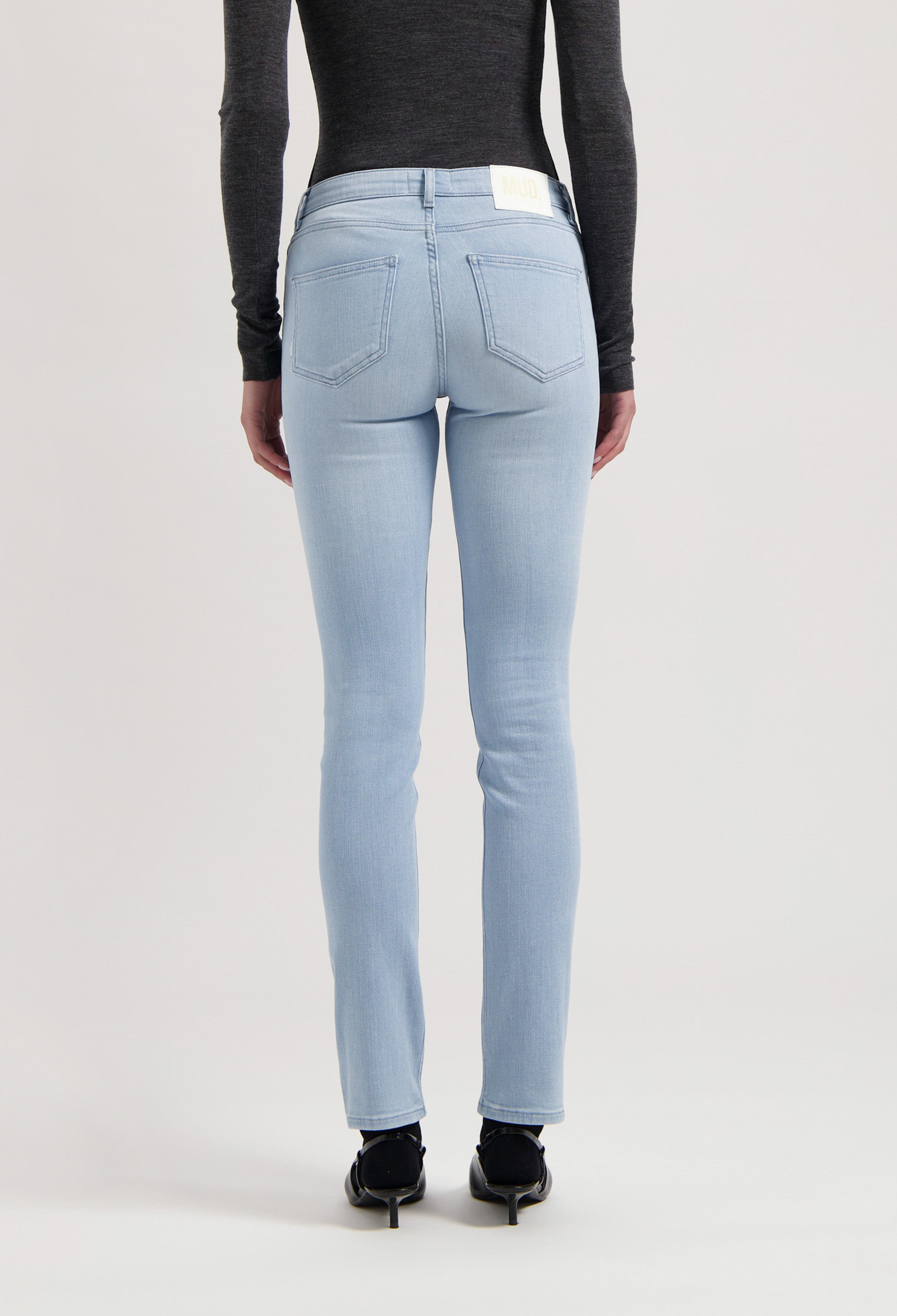 Light blue slim-fit jeans from MUD Jeans, crafted from organic cotton, shown with a charcoal gray long-sleeve top.