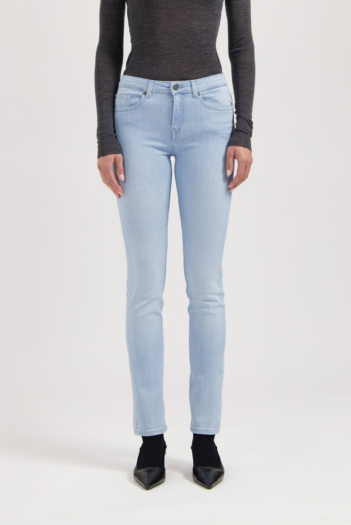 Light blue stretch jeans in slim-fit style, coupled with a dark gray long-sleeve top and black pointed shoes.