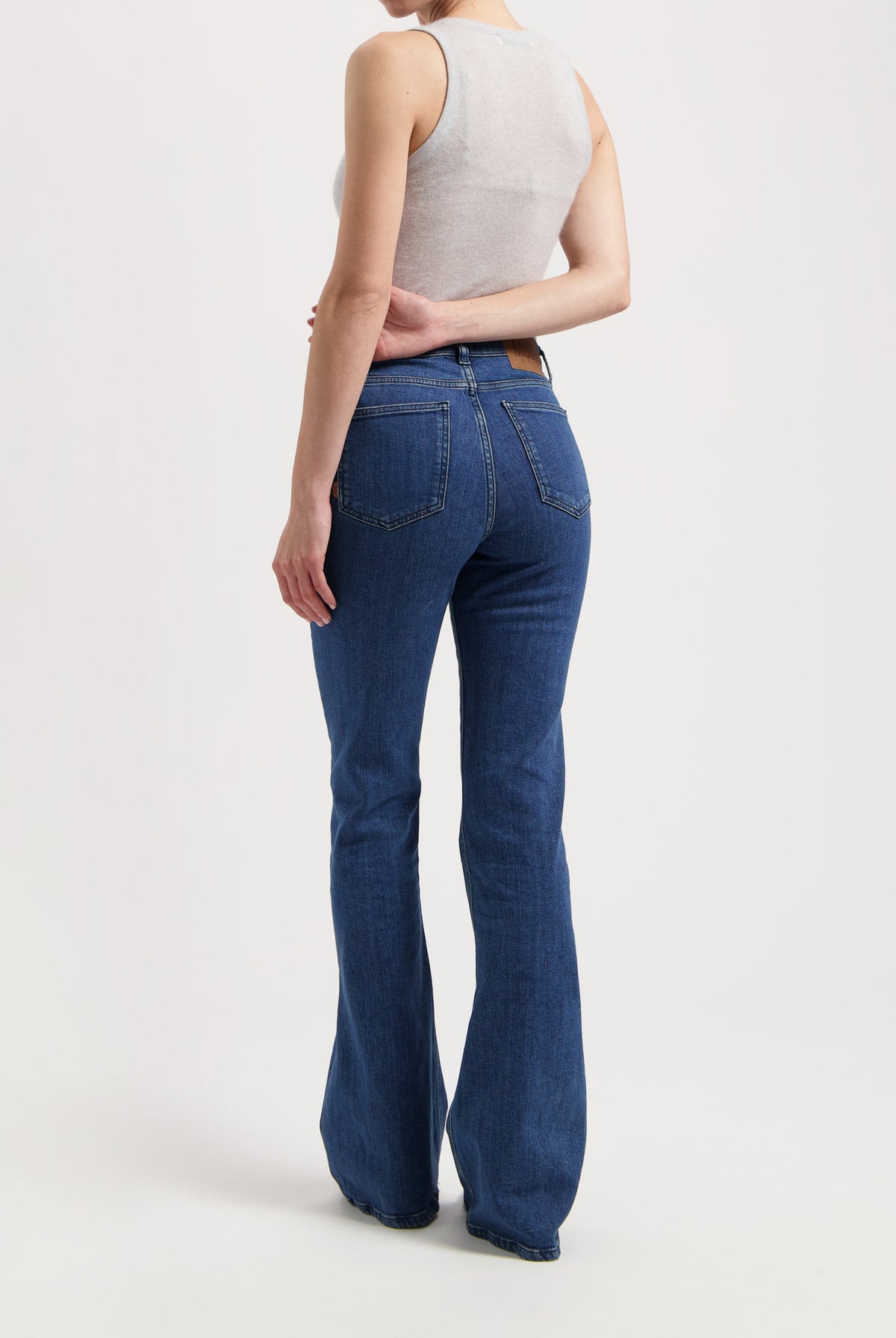 Blue high-waisted flared jeans paired with a white sleeveless top, showcasing a modern, casual look.