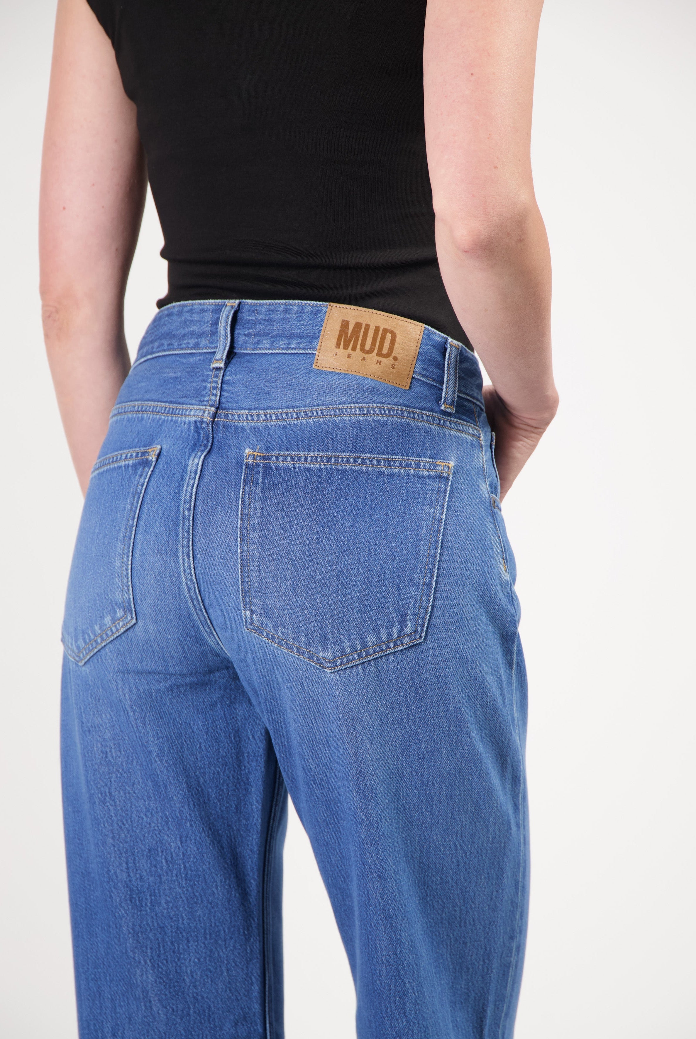 Back view of sustainable blue MUD Jeans made from organic cotton, showcasing classic cut and leather logo patch.