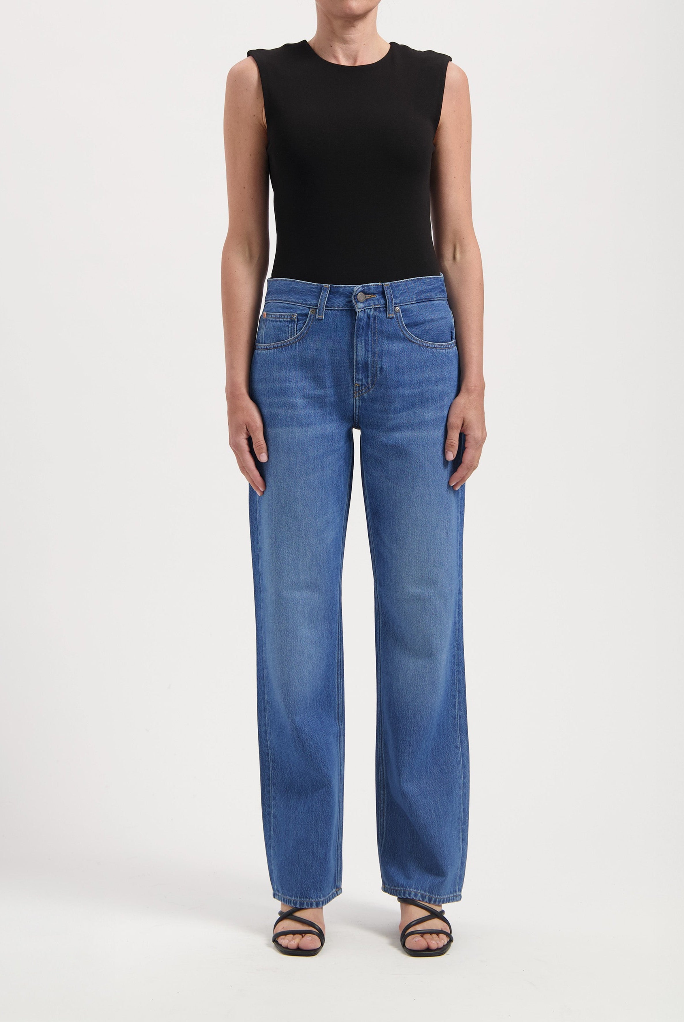 Wide-leg blue jeans paired with a sleeveless black top, demonstrating casual fashion with minimalist style.