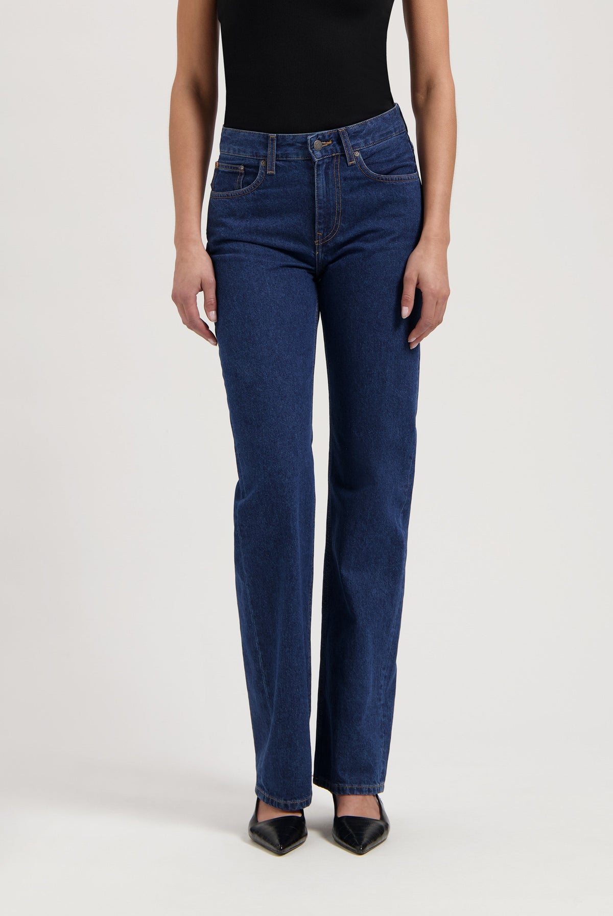 Dark indigo straight-leg jeans paired with a fitted black top, showcasing minimalist style and classic denim fit.