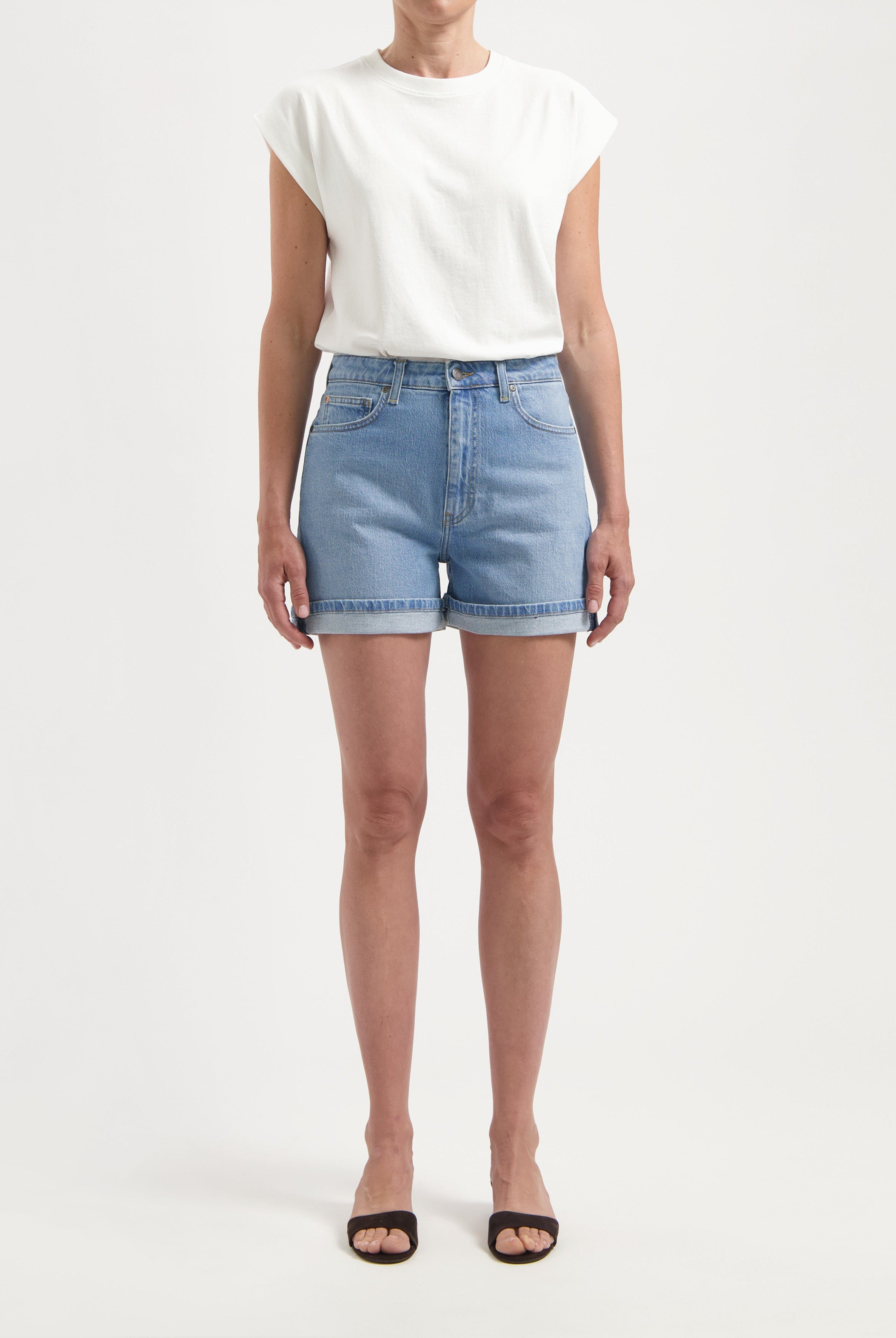 Light blue denim shorts paired with a casual white sleeveless top and black open-toe sandals for a fresh summer look.