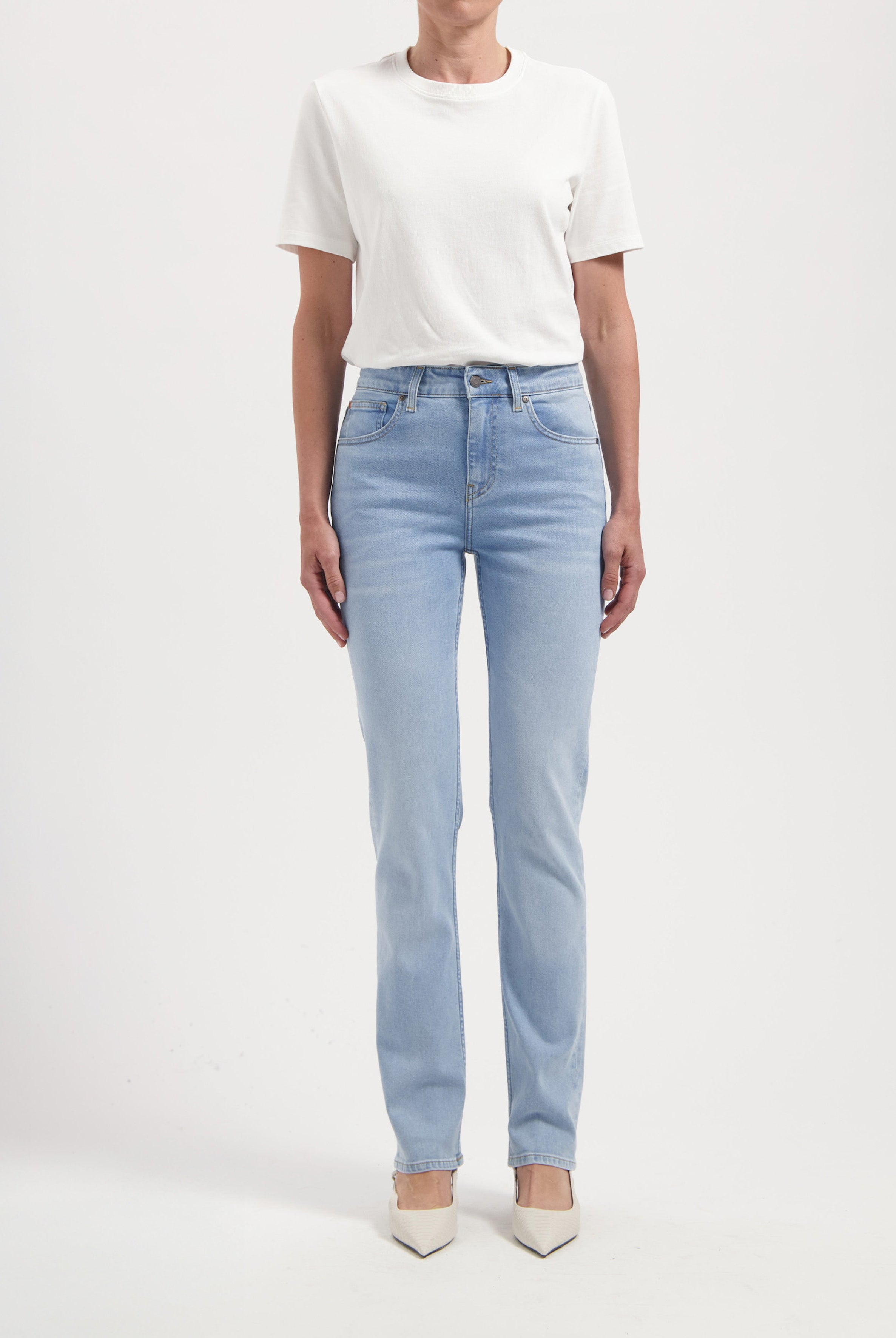 A pair of light blue straight-leg jeans paired with a simple white t-shirt, highlighting a casual fashion style.