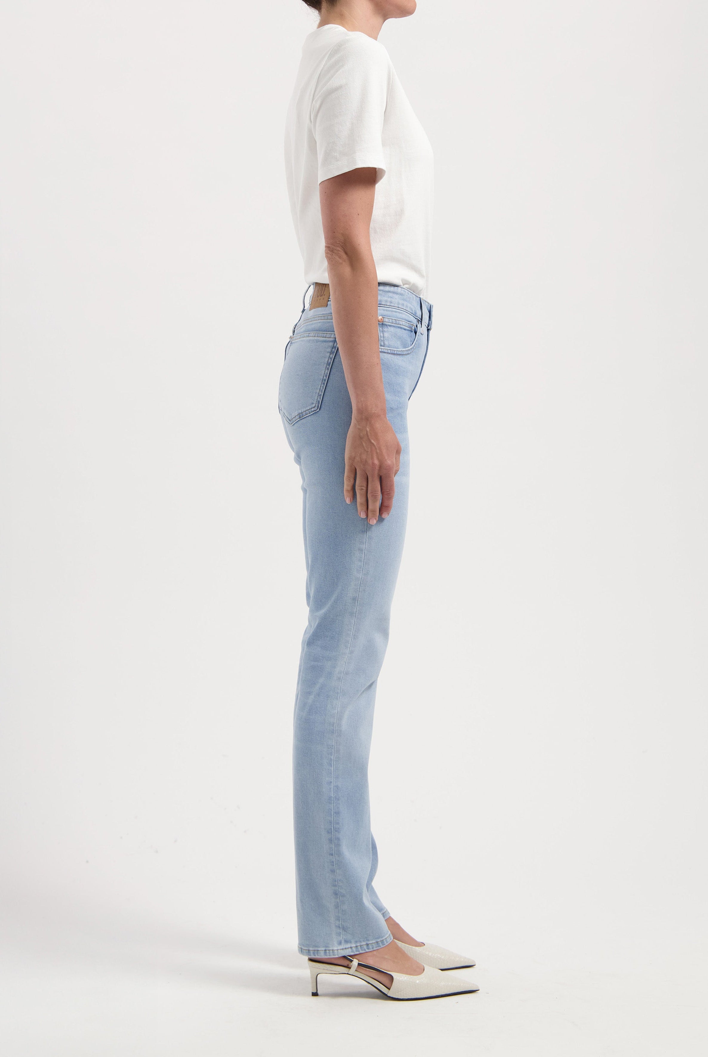 Model in light blue straight-leg jeans with a fitted white T-shirt, showcasing a side profile against a white background.