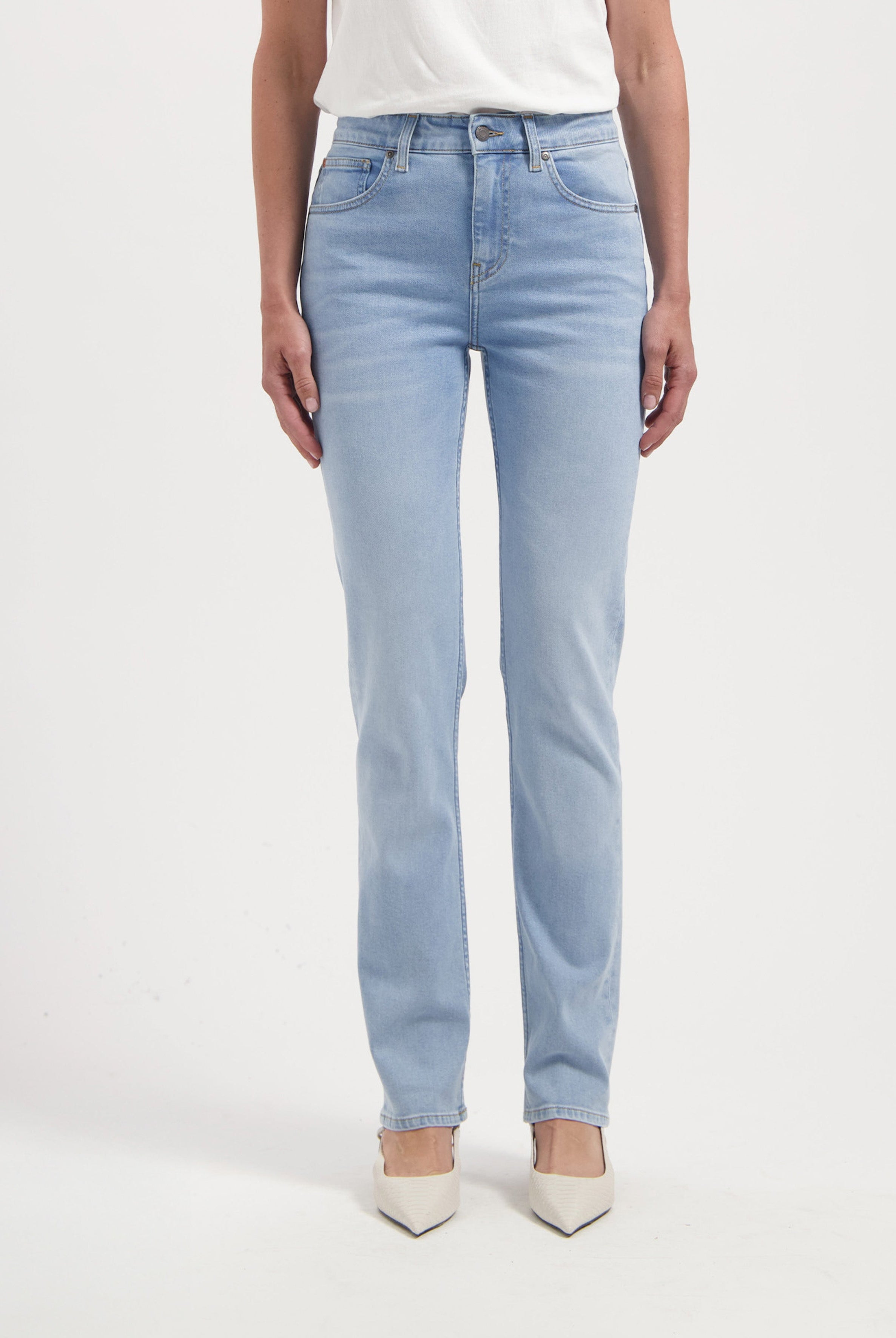 Light blue straight-cut denim jeans made from cotton, paired with an off-white top and white pointed-toe shoes.