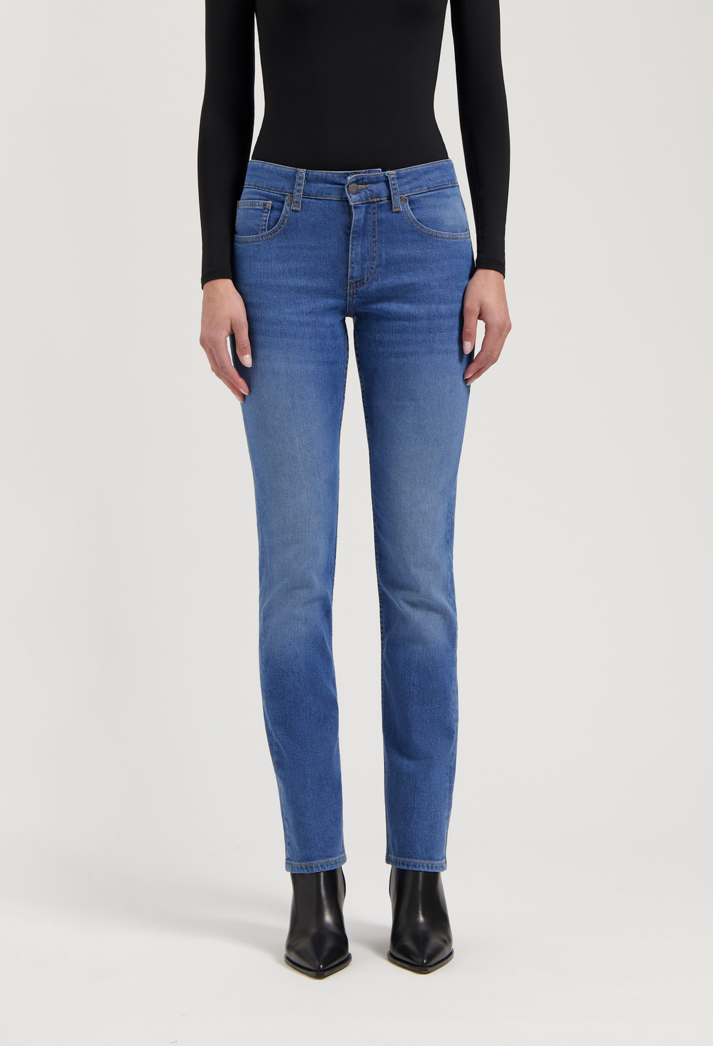 Classic blue denim jeans in a straight-leg cut, paired with a fitted black long-sleeve top and black ankle boots.