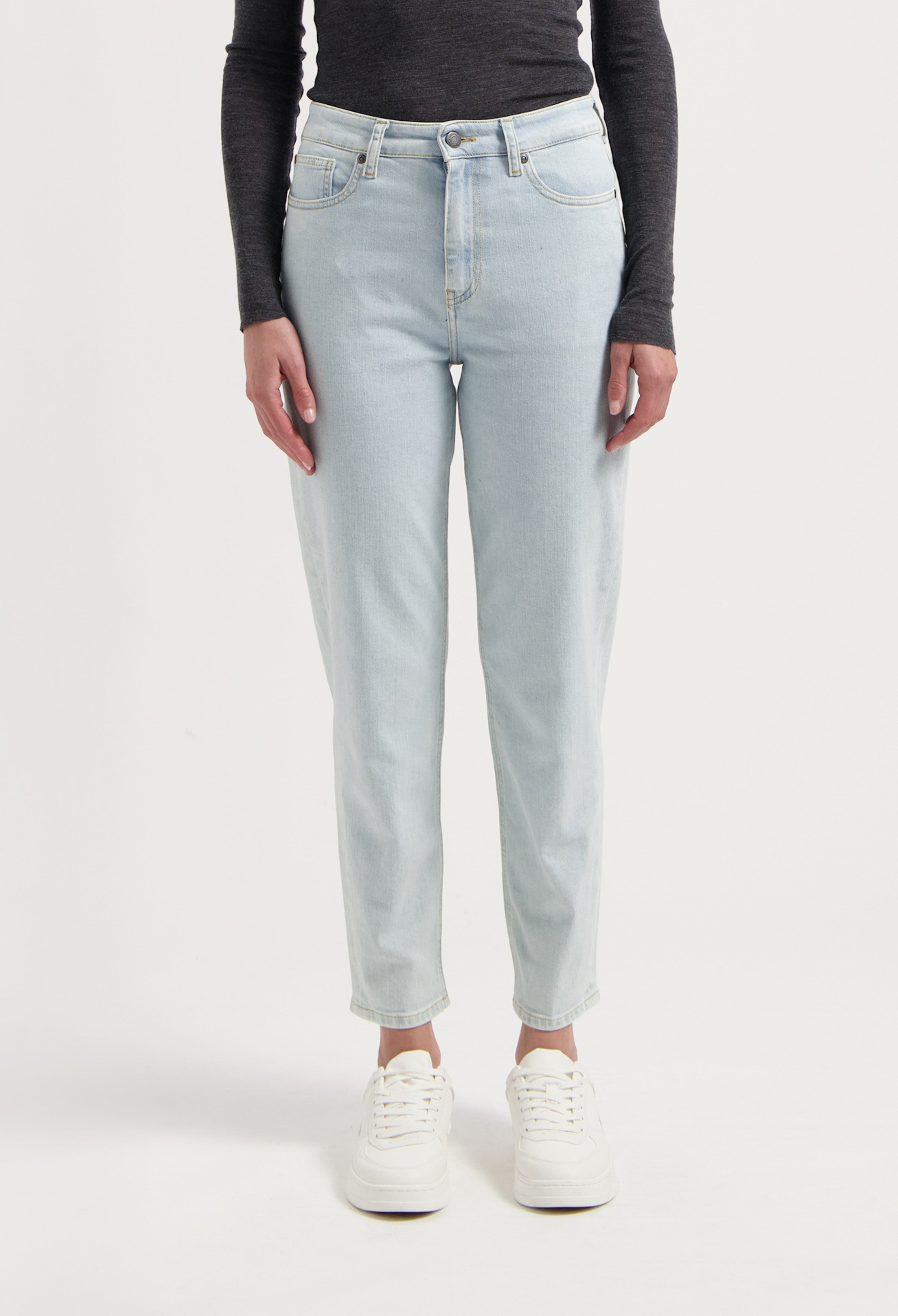 Light blue, high-waisted jeans with a tapered fit worn by a model, paired with a charcoal long-sleeve top and white sneakers.