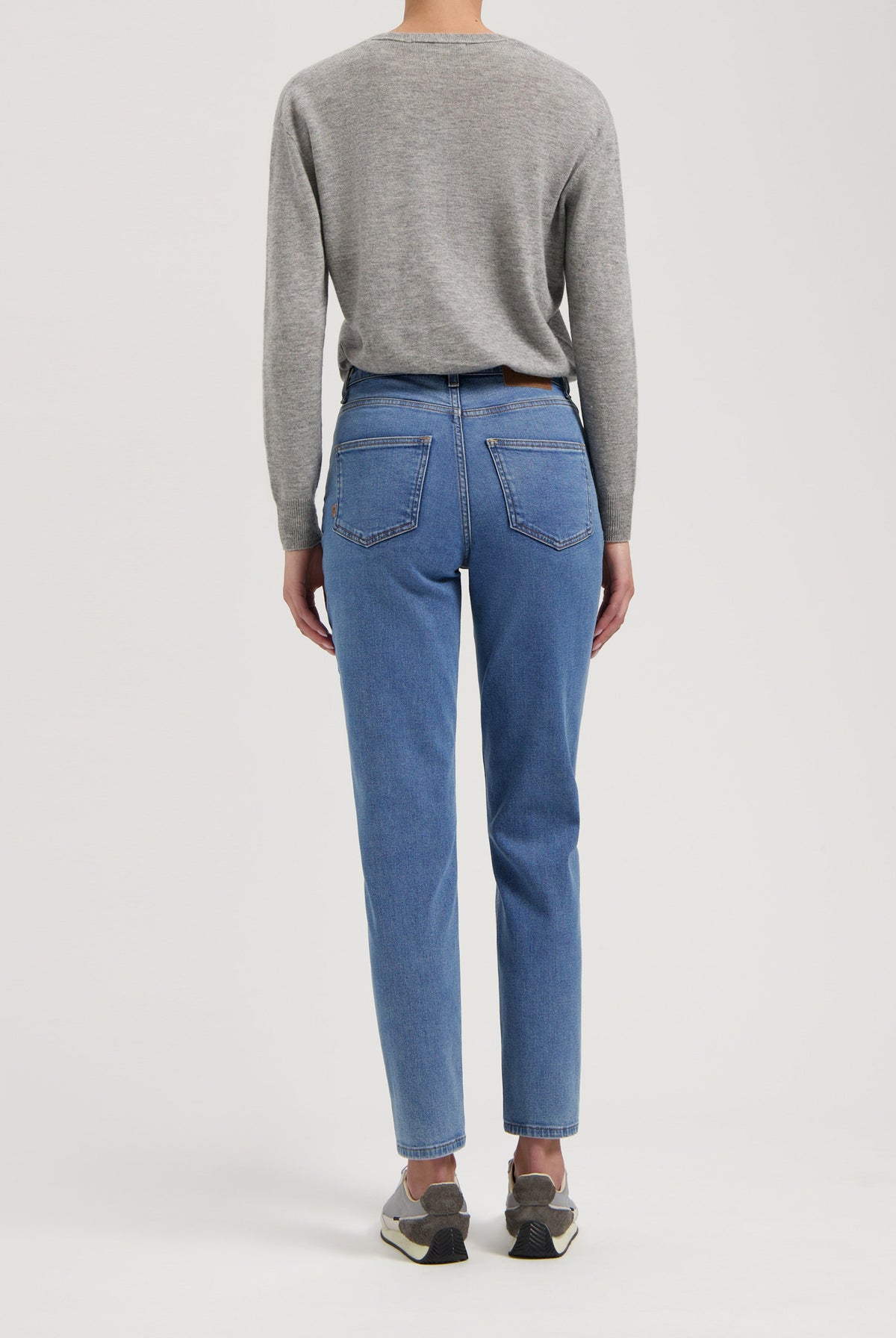 Gray long-sleeve top paired with classic blue high-waisted jeans, showcasing a casual and comfortable style from the back.