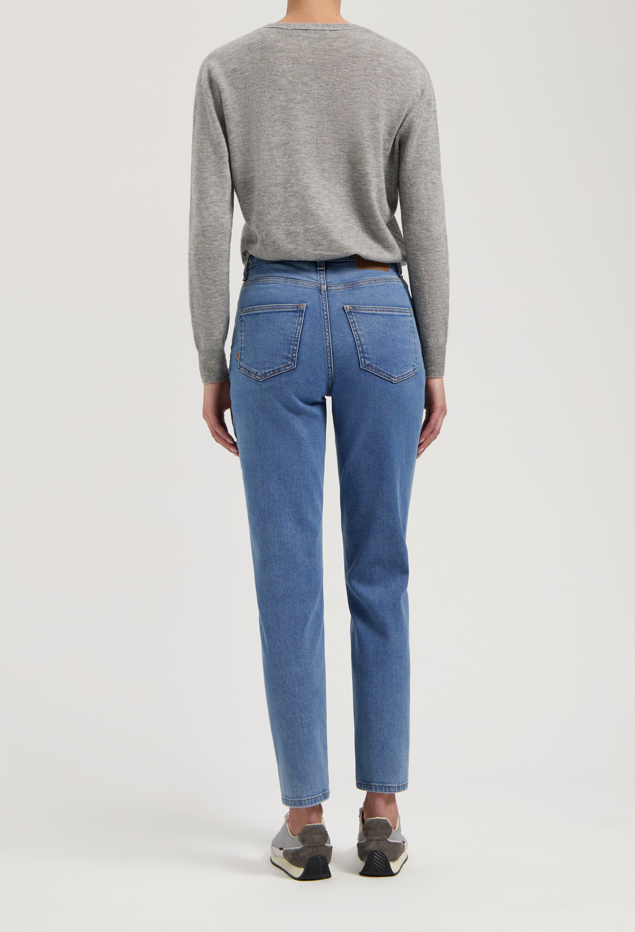 Gray long-sleeve top paired with classic blue high-waisted jeans, showcasing a casual and comfortable style from the back.