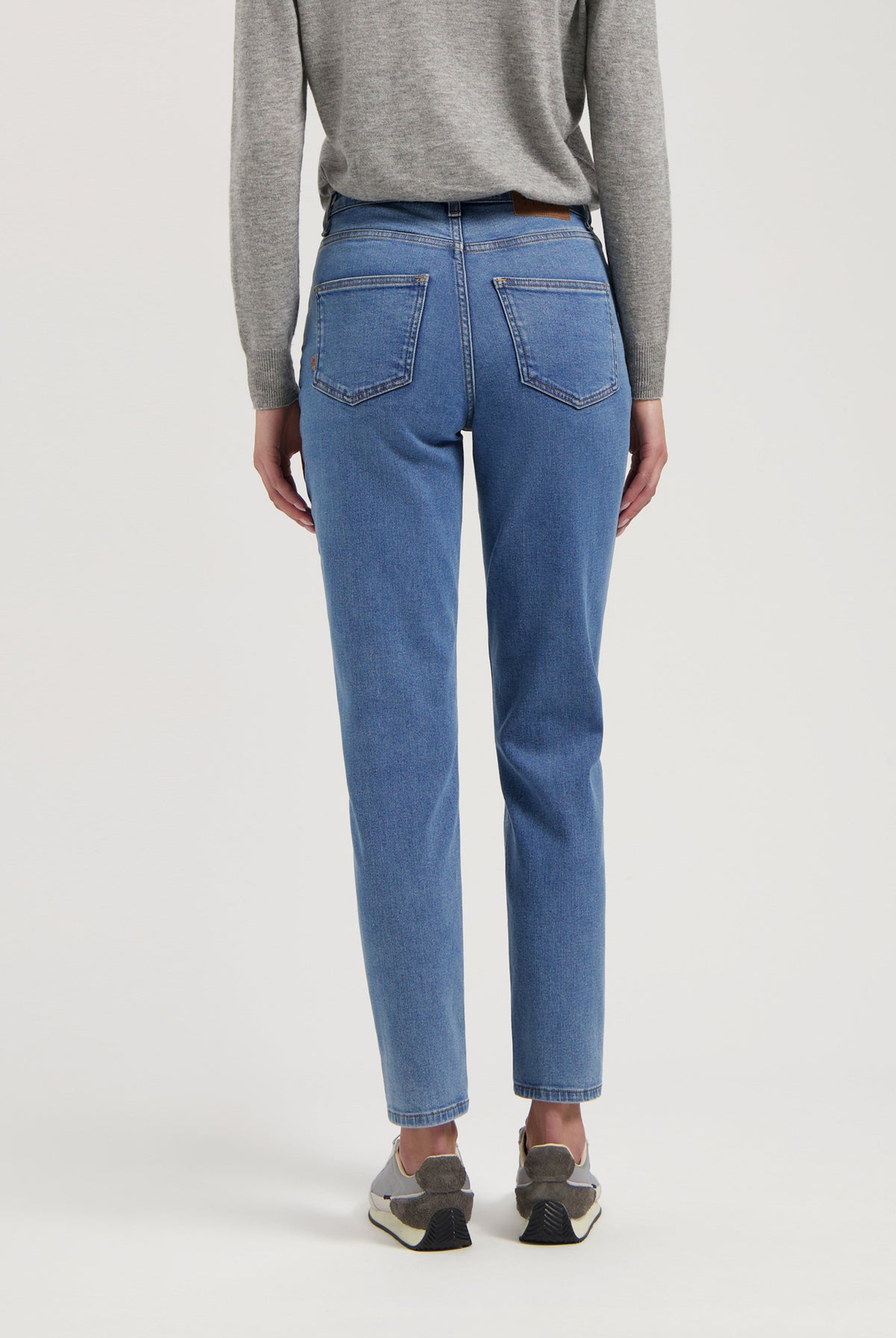 Casual light blue straight-leg jeans paired with a cozy gray sweater, showcasing a modern, comfortable everyday style.