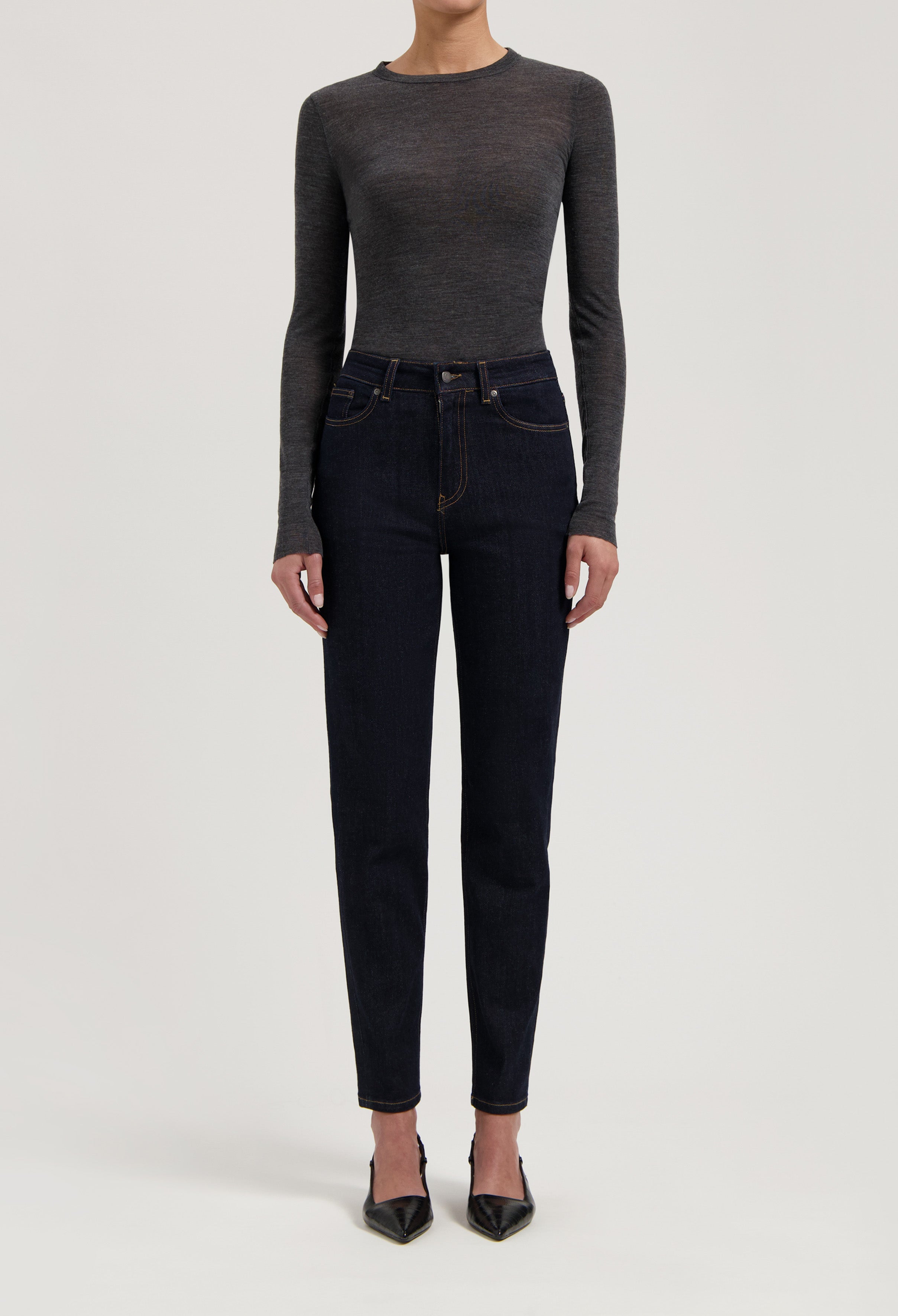 Dark blue, high-waisted denim jeans paired with a fitted, long-sleeved, charcoal gray top and black pointed-toe heels.