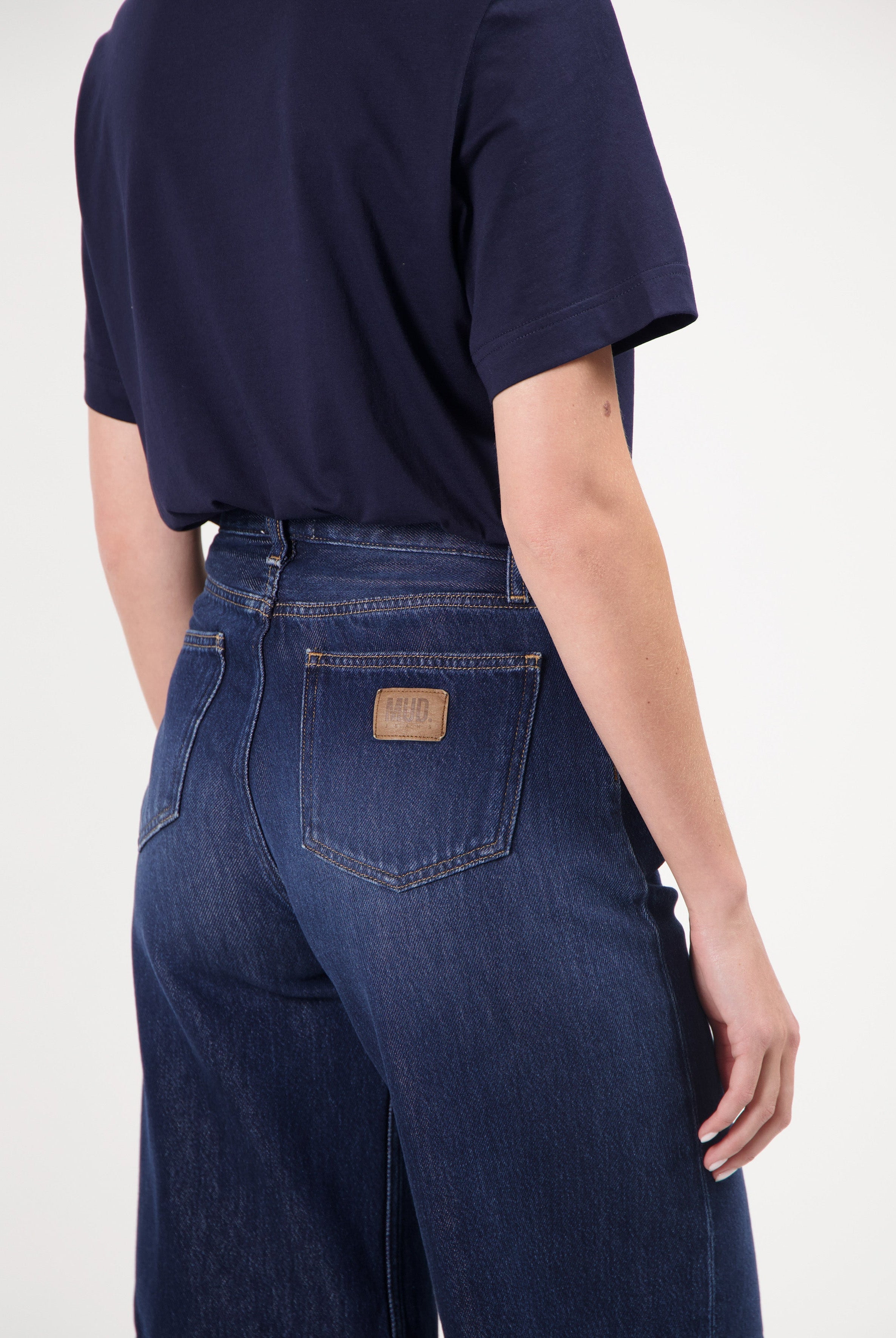 Dark blue wide-leg MUD Jeans made from organic cotton, showcasing a back view paired with a black short-sleeve top.
