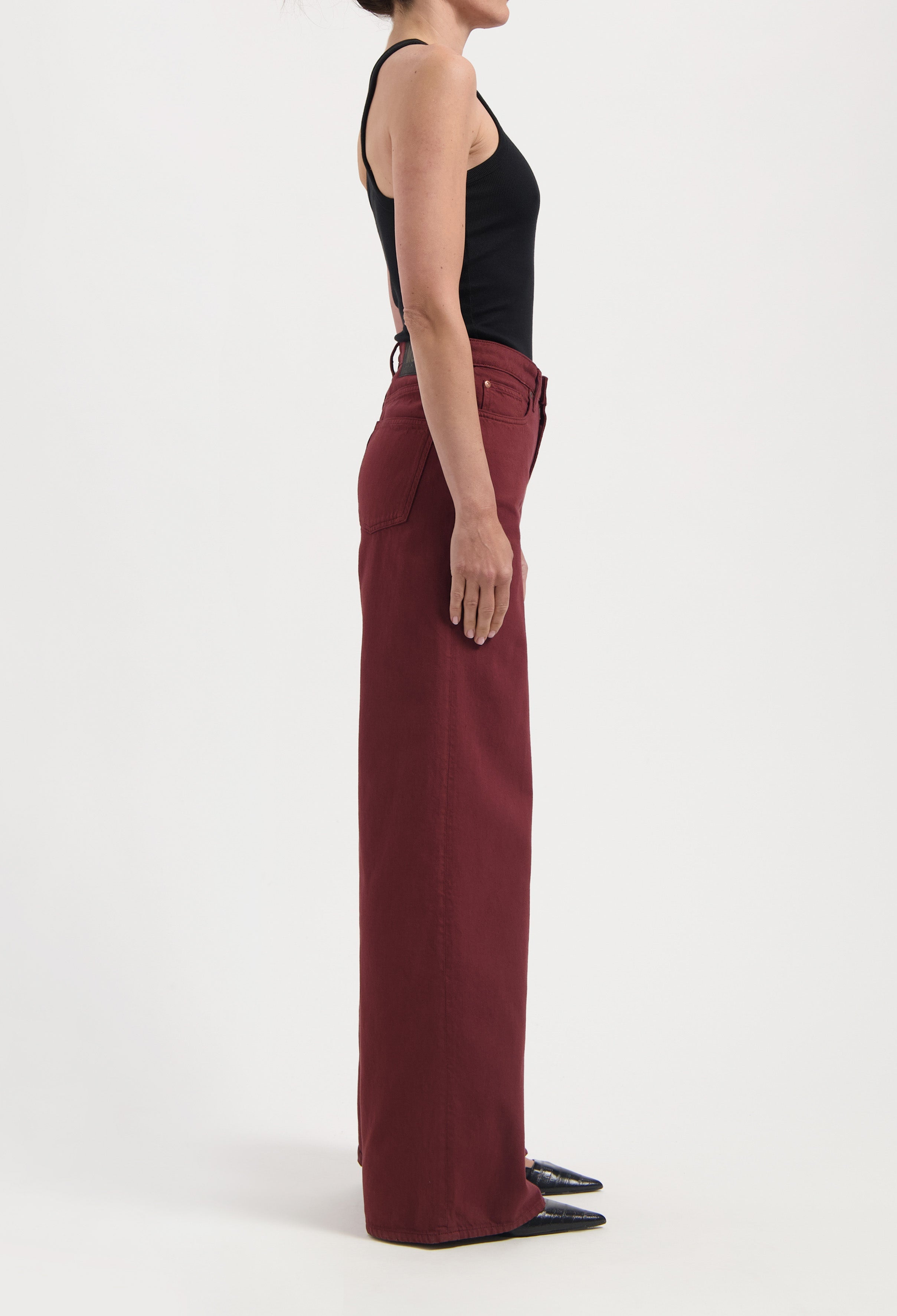 Wide-leg burgundy trousers styled with a black sleeveless top, highlighting a chic, minimalist fashion look.