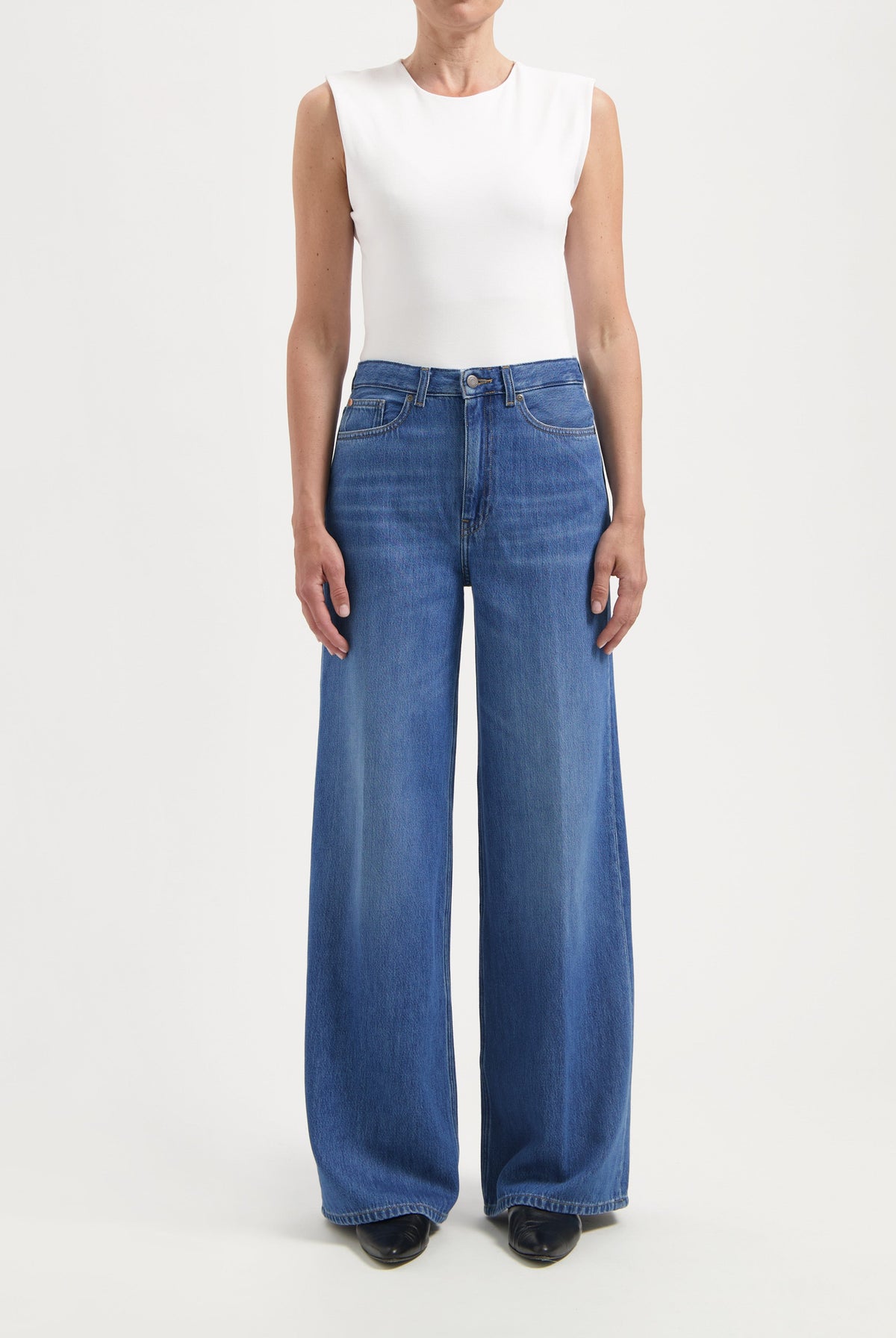 Wide-leg blue denim jeans paired with a white sleeveless top, showcasing a casual yet stylish outfit.