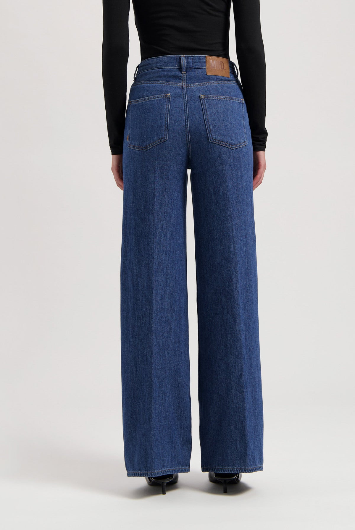 Wide-leg denim jeans in classic blue, featuring high-rise waist and rear pockets, paired with a sleek black long-sleeve top.