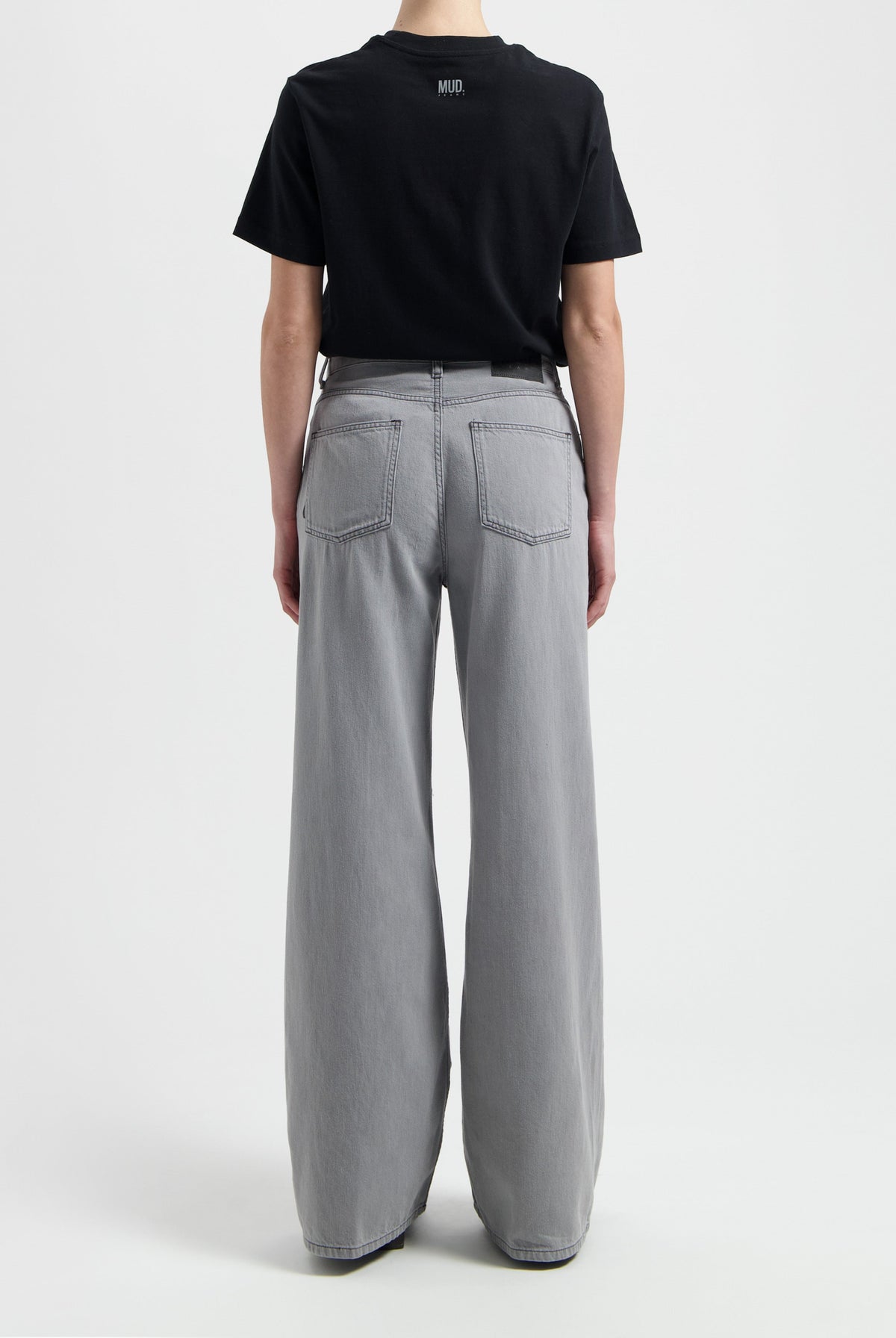 Wide-leg gray MUD Jeans made from organic cotton, shown from the back paired with a black short-sleeve t-shirt.