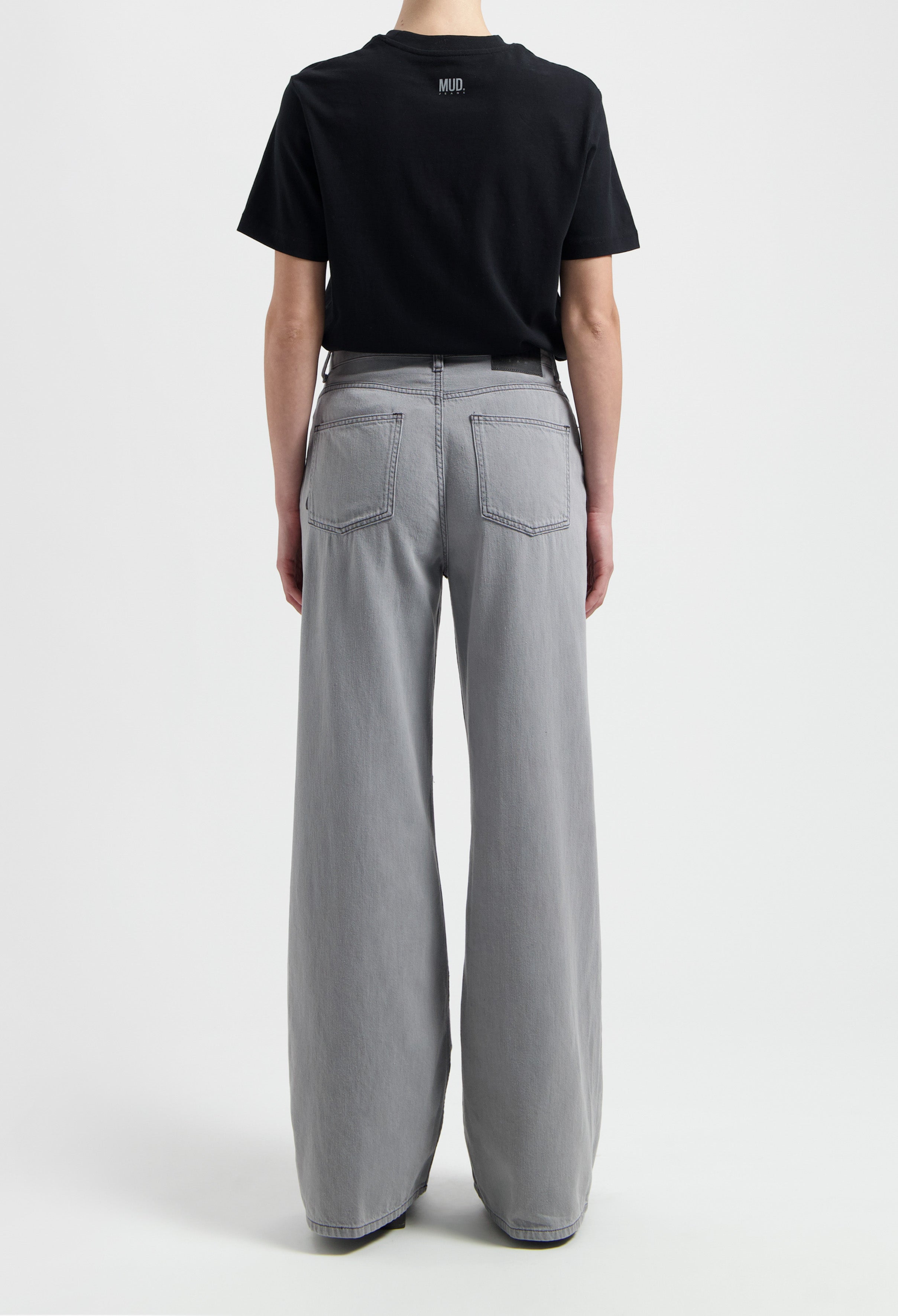 Wide-leg gray MUD Jeans made from organic cotton, shown from the back paired with a black short-sleeve t-shirt.