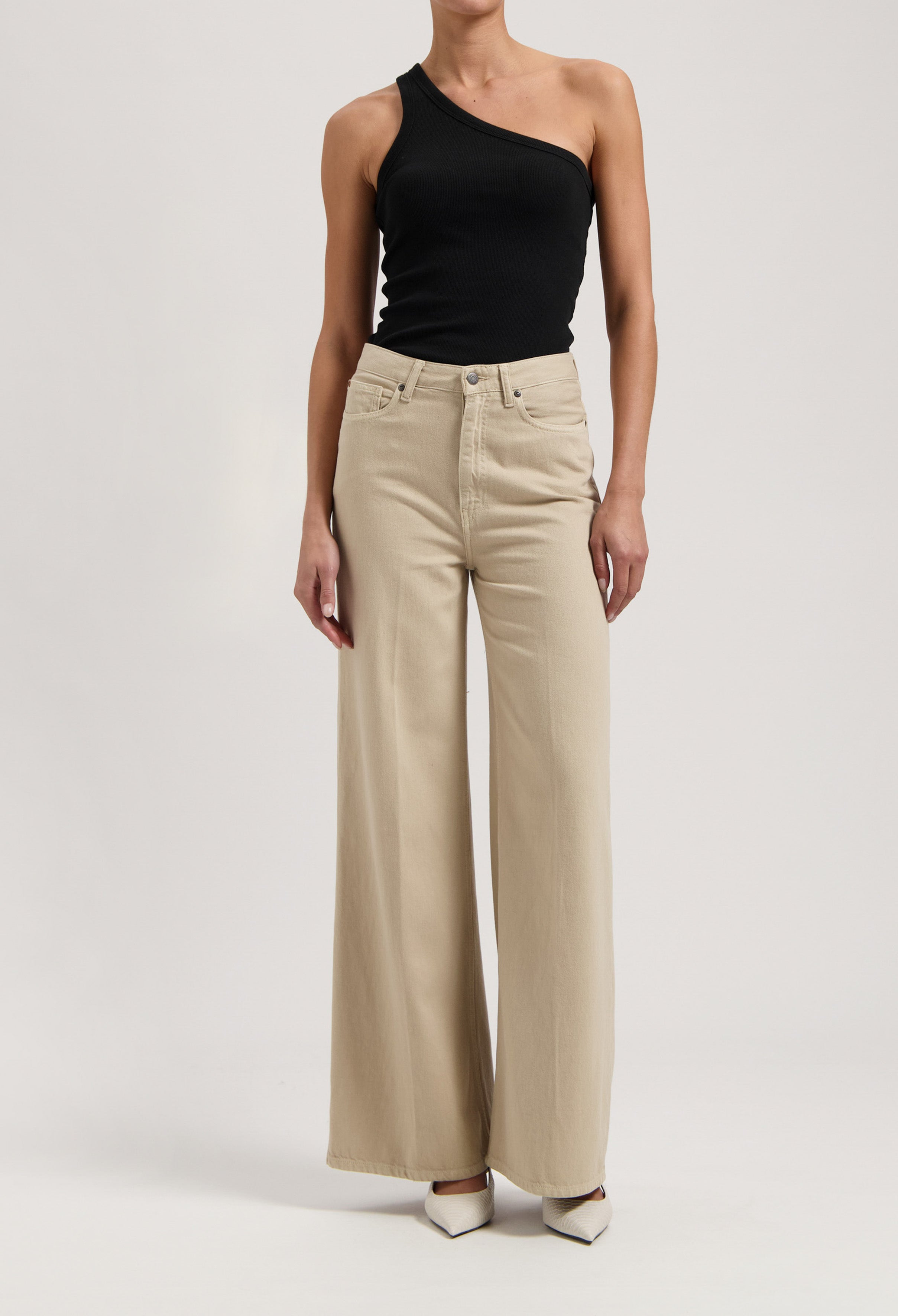 Wide-legged beige trousers paired with a black one-shoulder top, showcasing an elegant and modern look.
