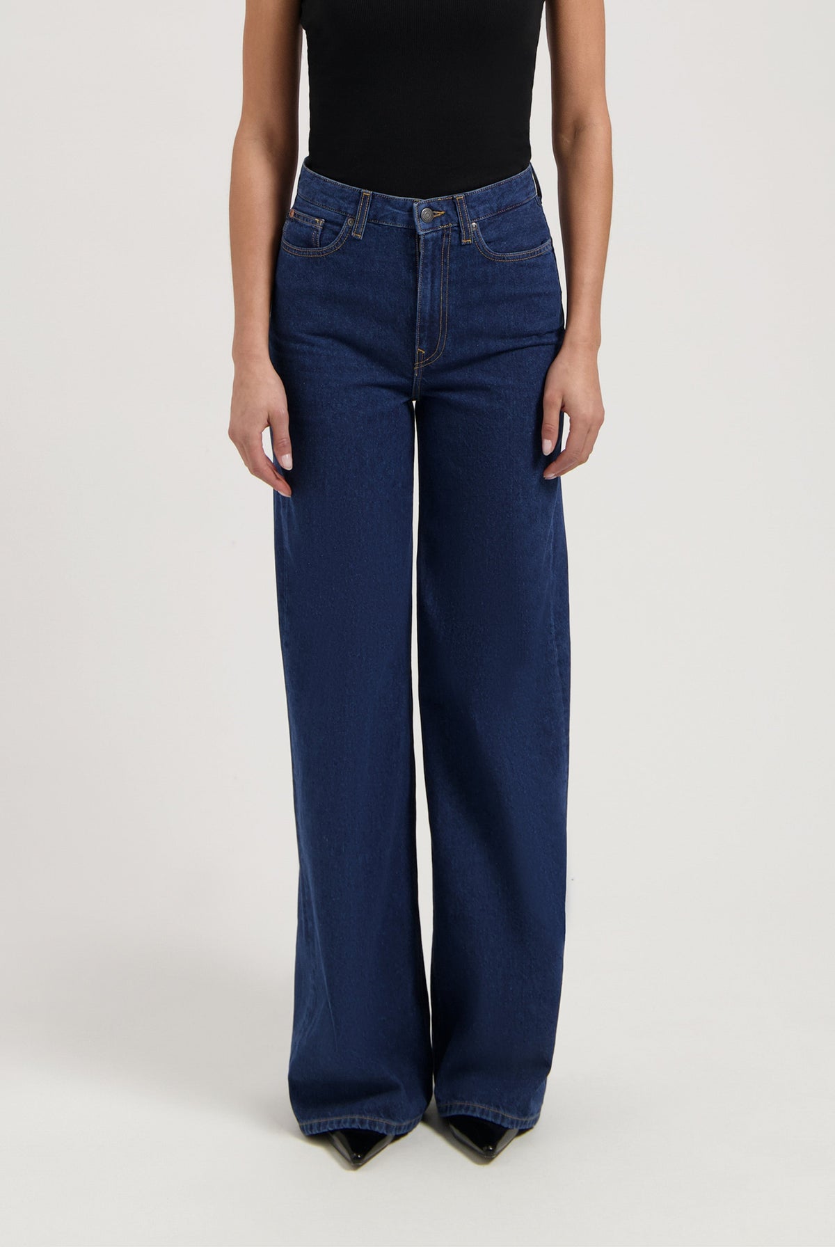Wide-leg blue denim jeans paired with a black sleeveless top, showing high-waisted style and casual elegance.