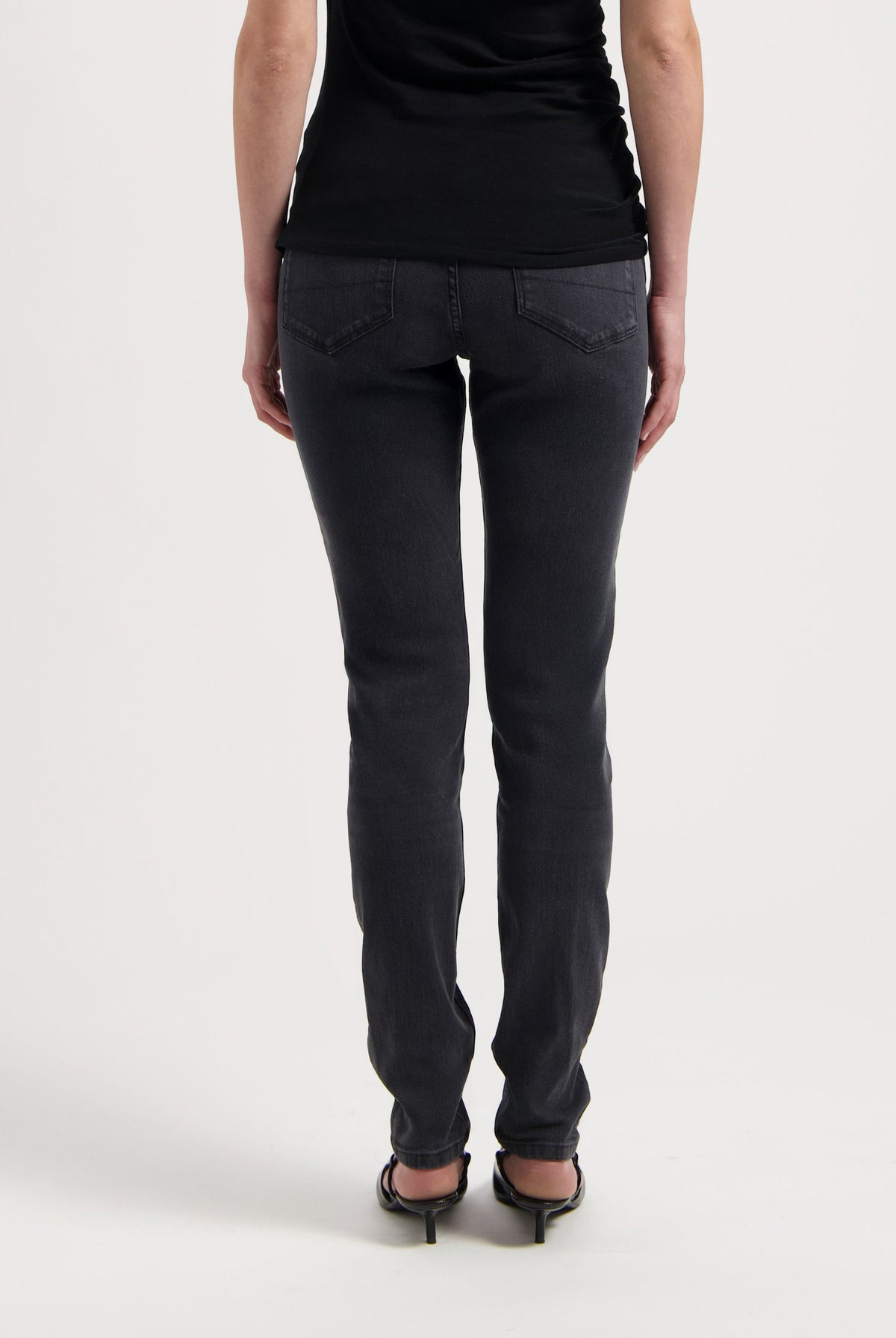 Black slim-fit jeans made from soft denim, showcasing rear view with decorative stitching and high heels for an elegant look.