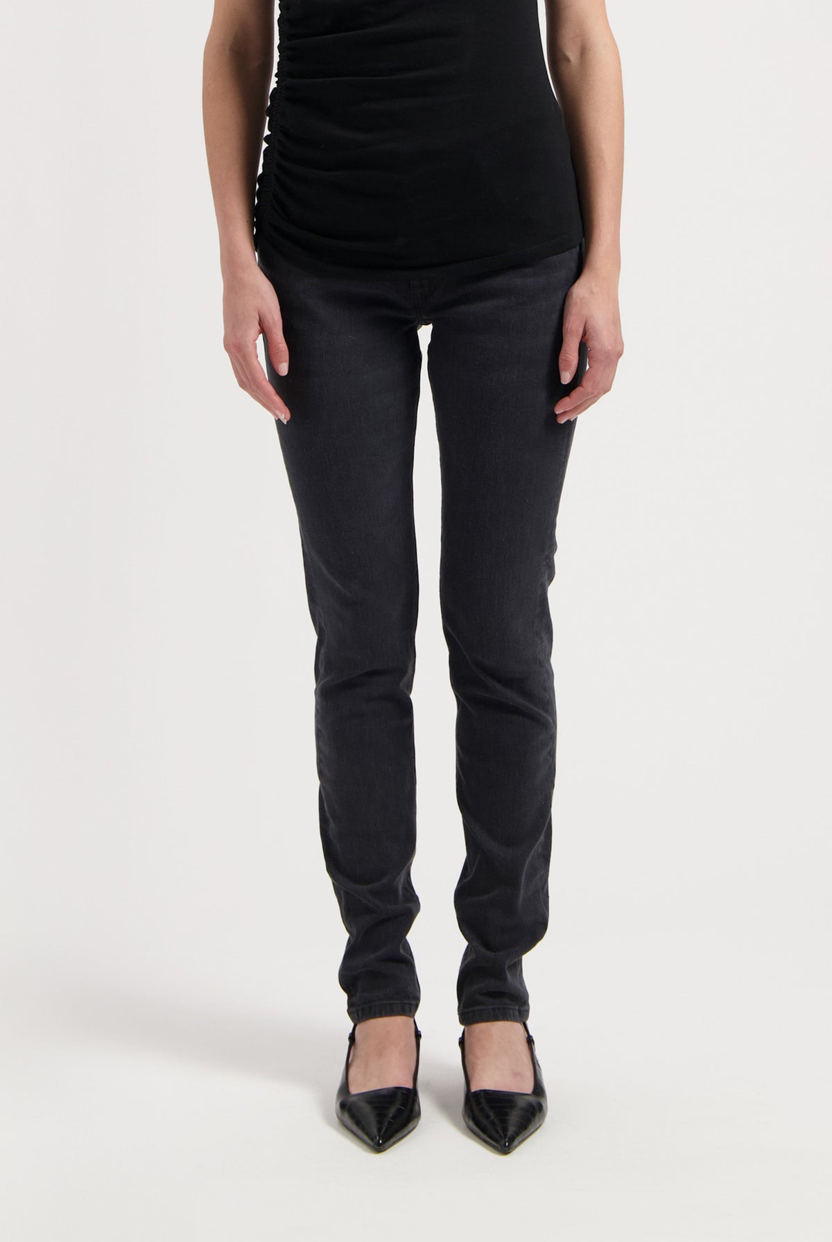 Chic black slim-fit pants paired with a sleeveless top and pointed black heels on white background, highlighting stylish casual wear.