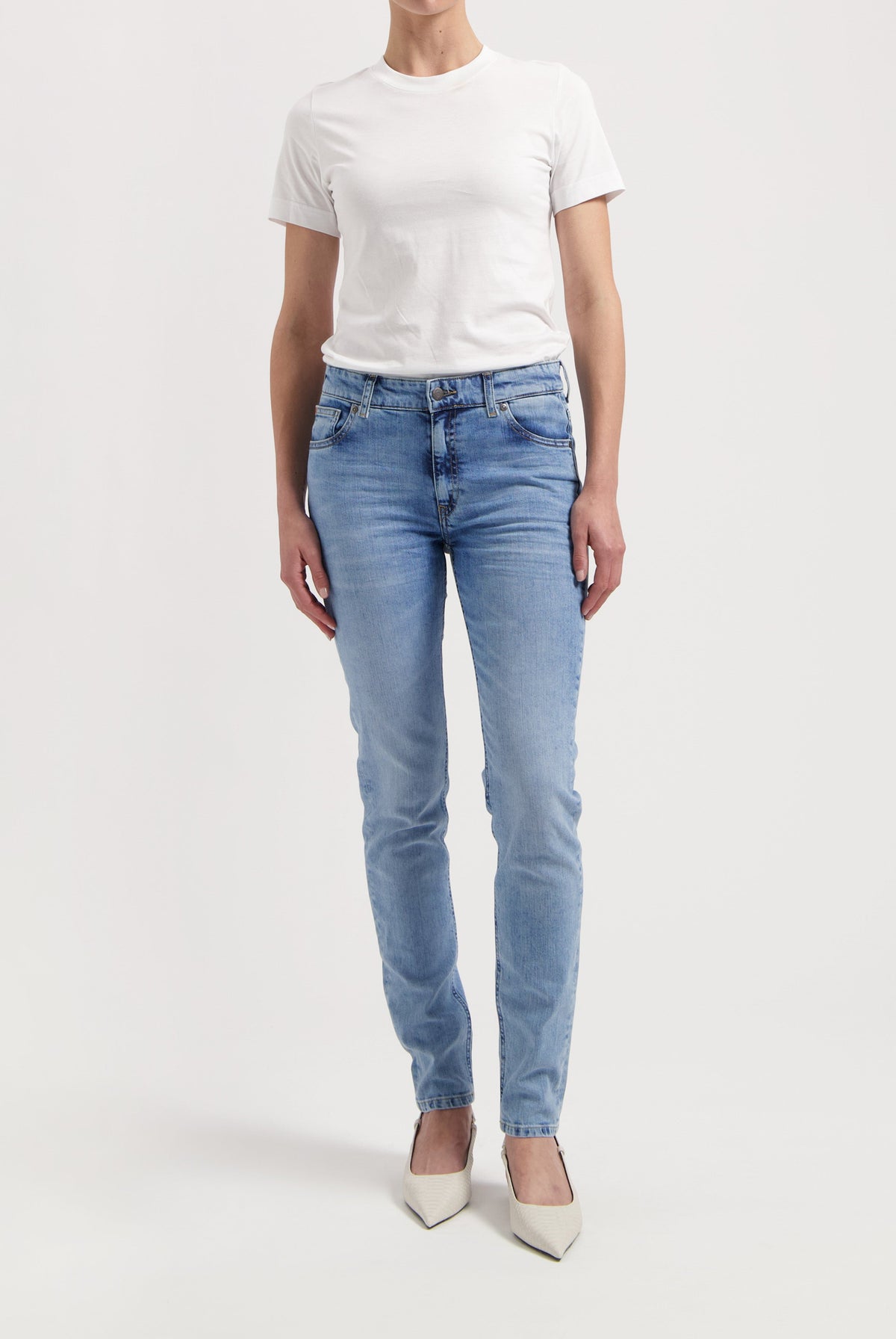 Casual chic outfit with light blue slim-fit jeans paired with a plain white T-shirt and pointy white heels.