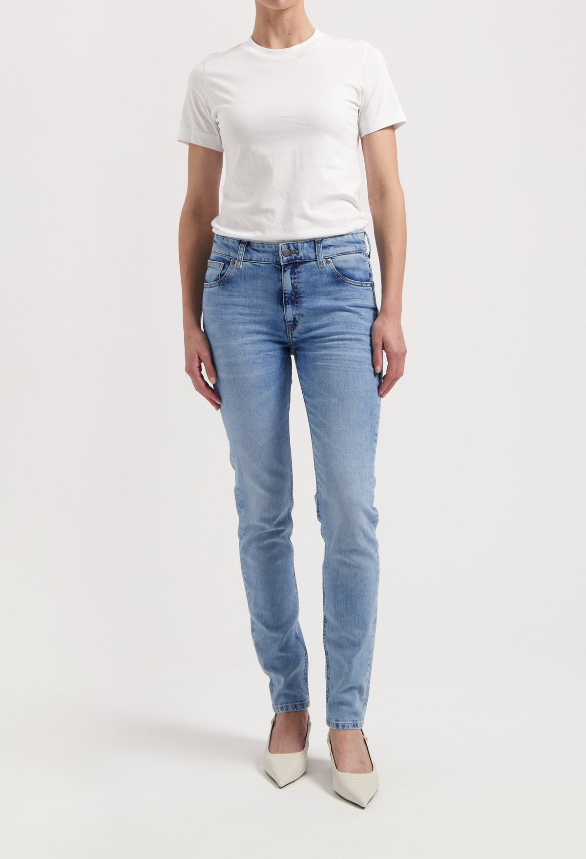 Casual chic outfit with light blue slim-fit jeans paired with a plain white T-shirt and pointy white heels.
