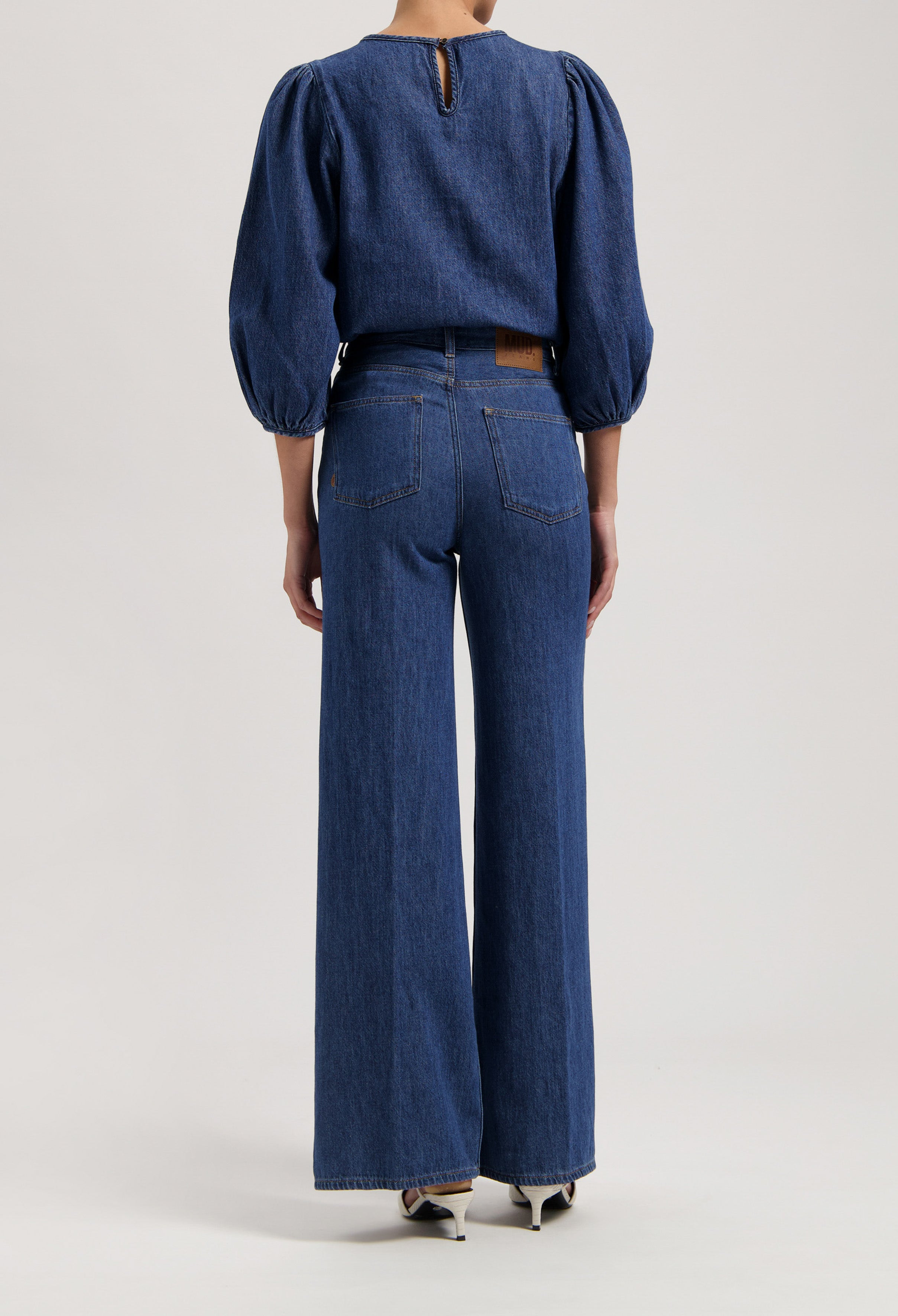 Back view of a denim outfit with wide-leg jeans and a puff-sleeve top, showcasing classic blue denim fabric.