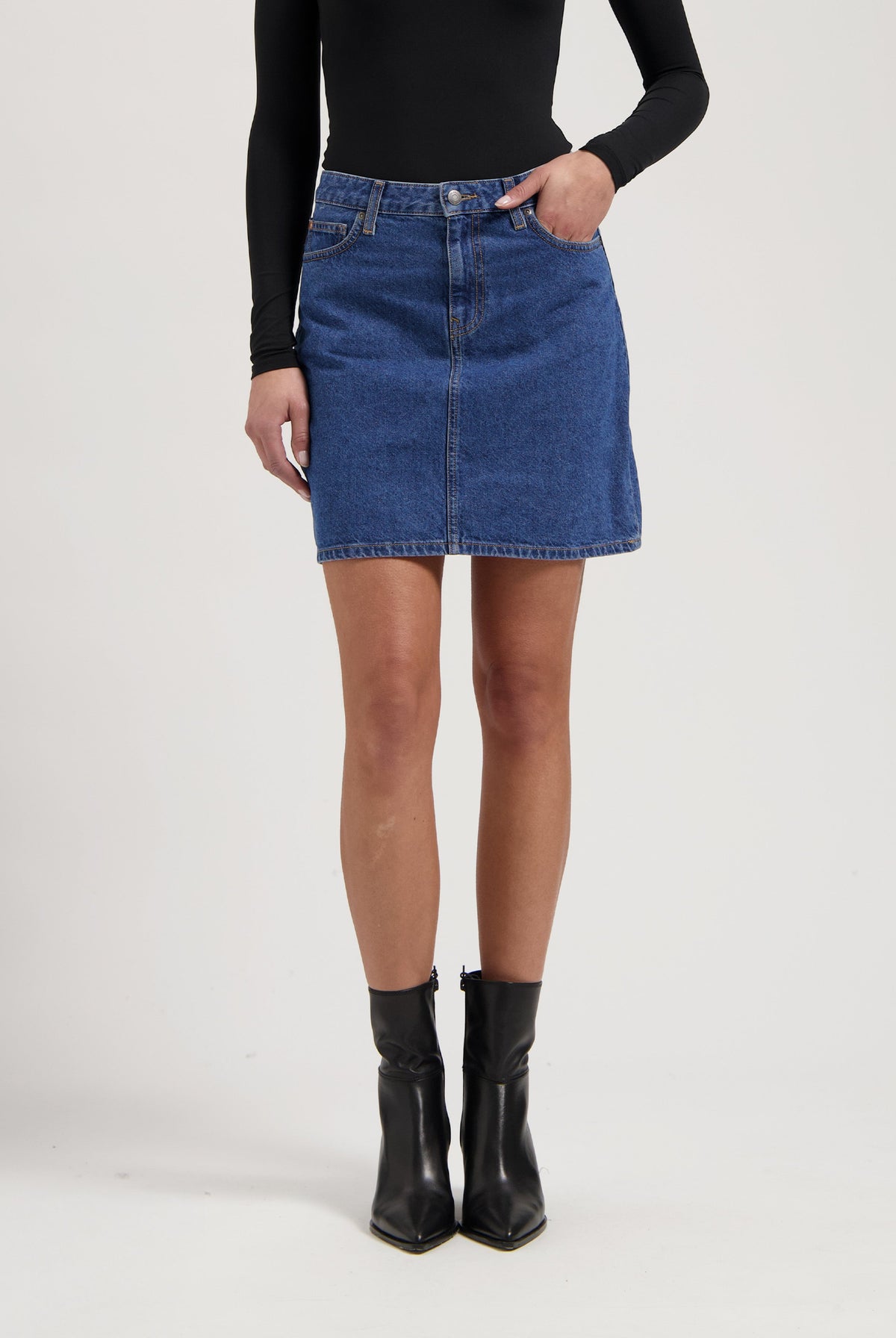 Blue denim skirt paired with a black long-sleeve top and black ankle boots, highlighting casual chic fashion style.