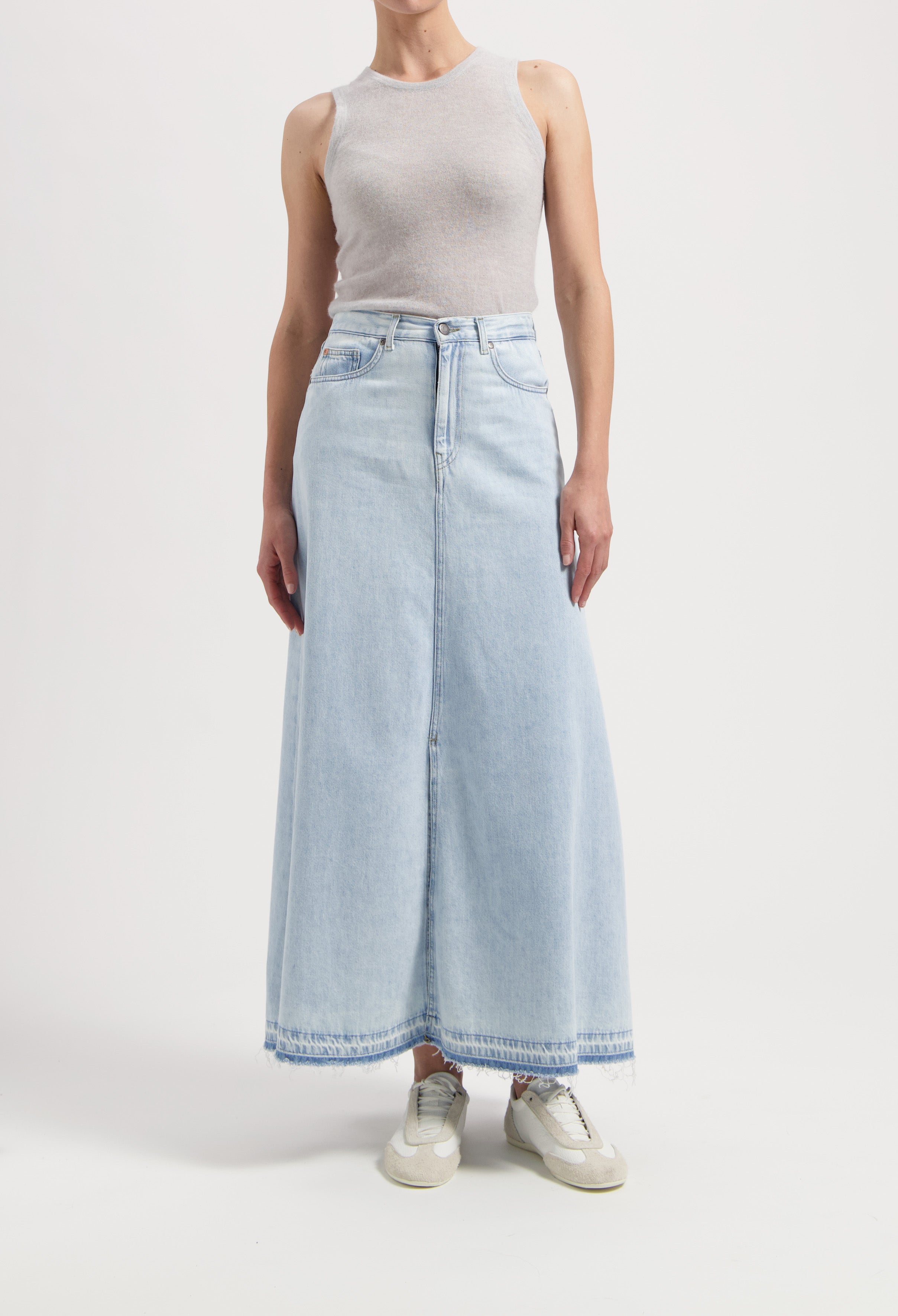Light blue denim maxi skirt paired with a sleeveless gray top, styled with casual beige sneakers.