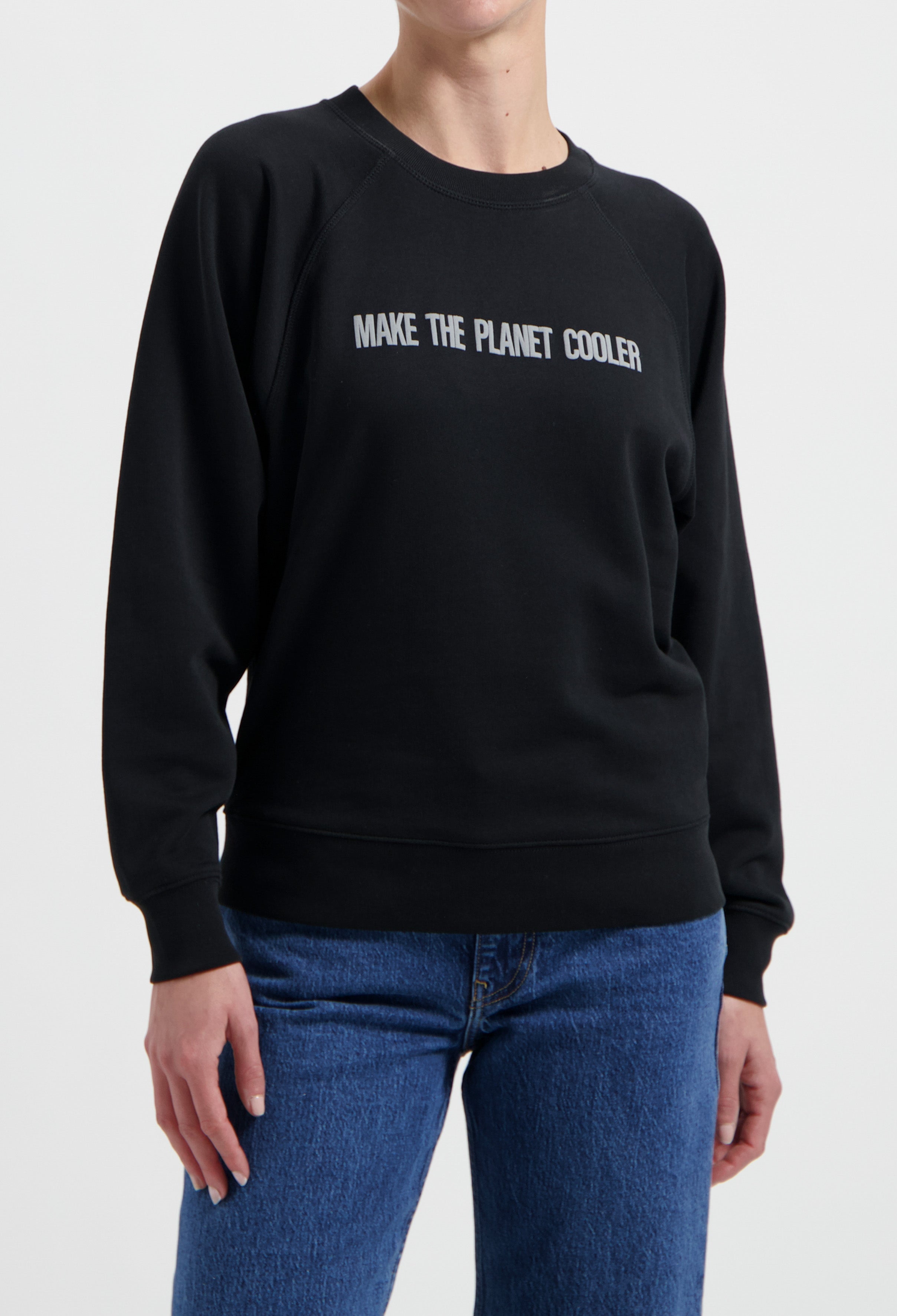 Black sweatshirt with "Make the Planet Cooler" text, paired with blue denim jeans, eco-friendly casual fashion style.