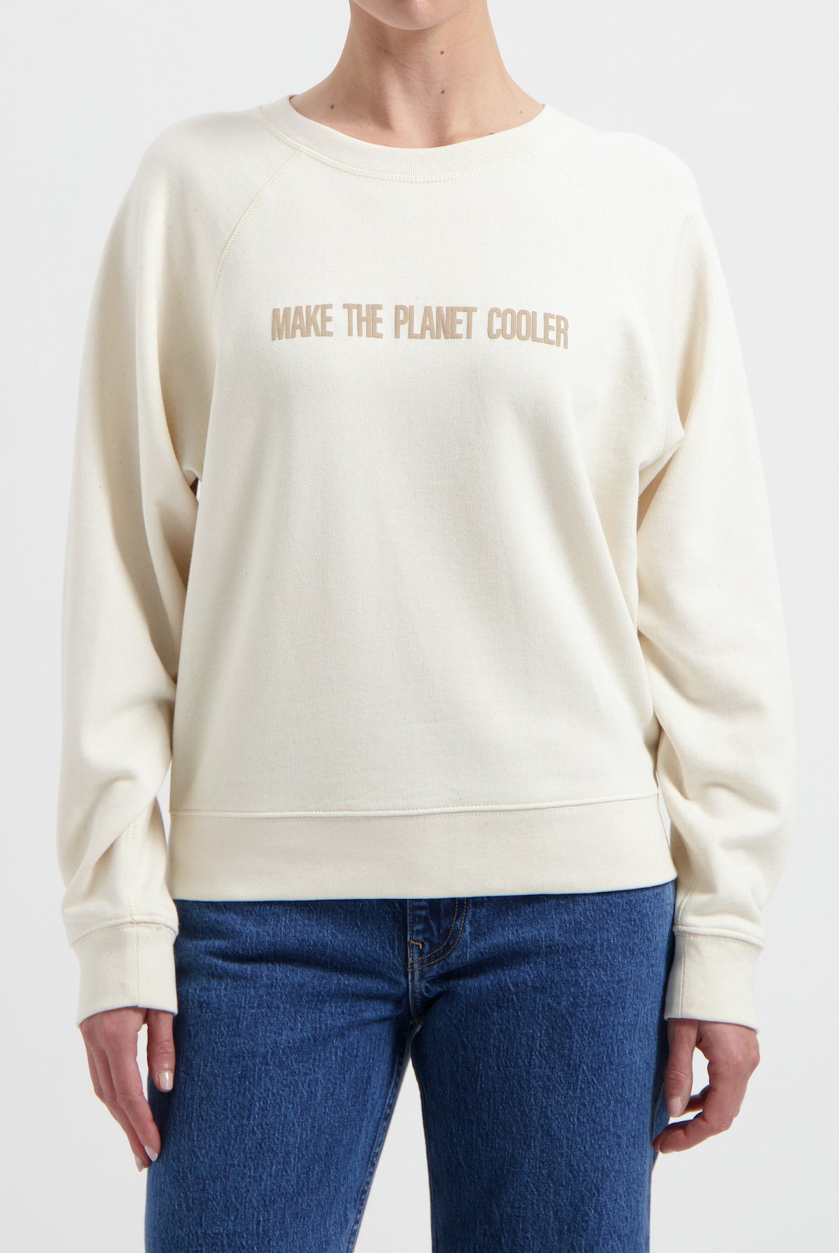 Ivory crew neck sweatshirt with a "Make the Planet Cooler" slogan, paired with classic blue denim jeans.