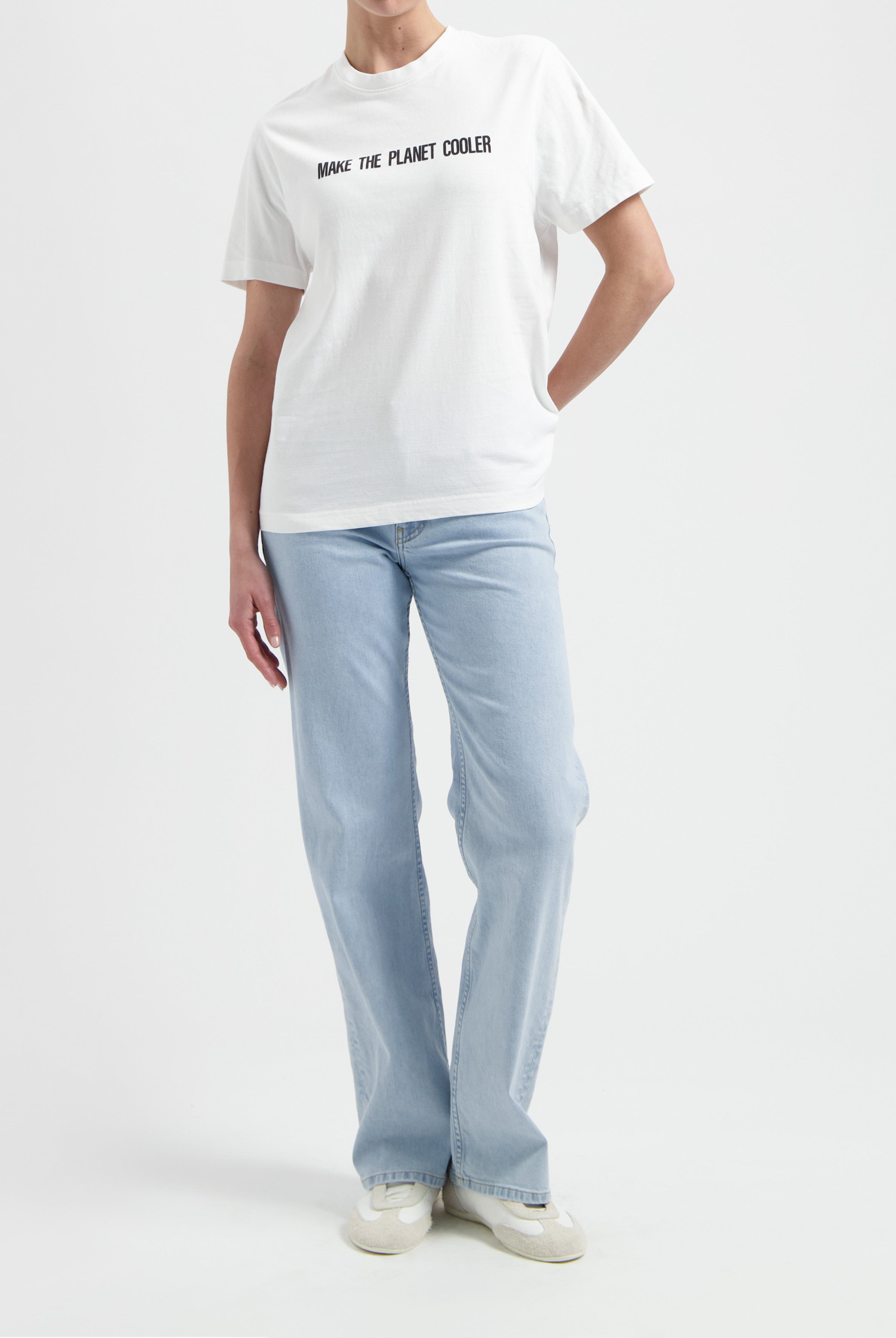 Casual white T-shirt with "Make the Planet Cooler" slogan, paired with light blue, straight-leg jeans and white sneakers.