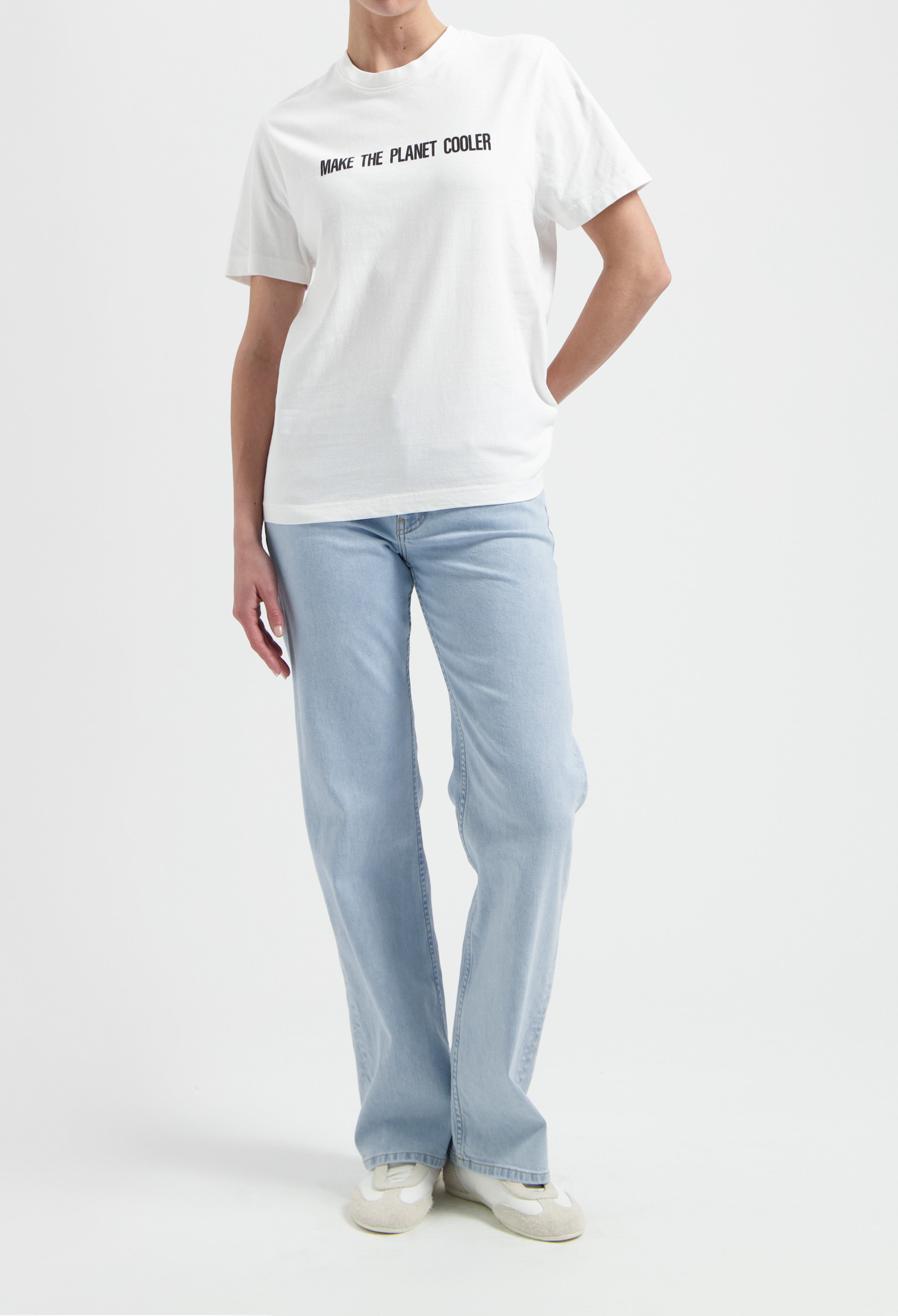 Casual white T-shirt with "Make the Planet Cooler" slogan, paired with light blue, straight-leg jeans and white sneakers.